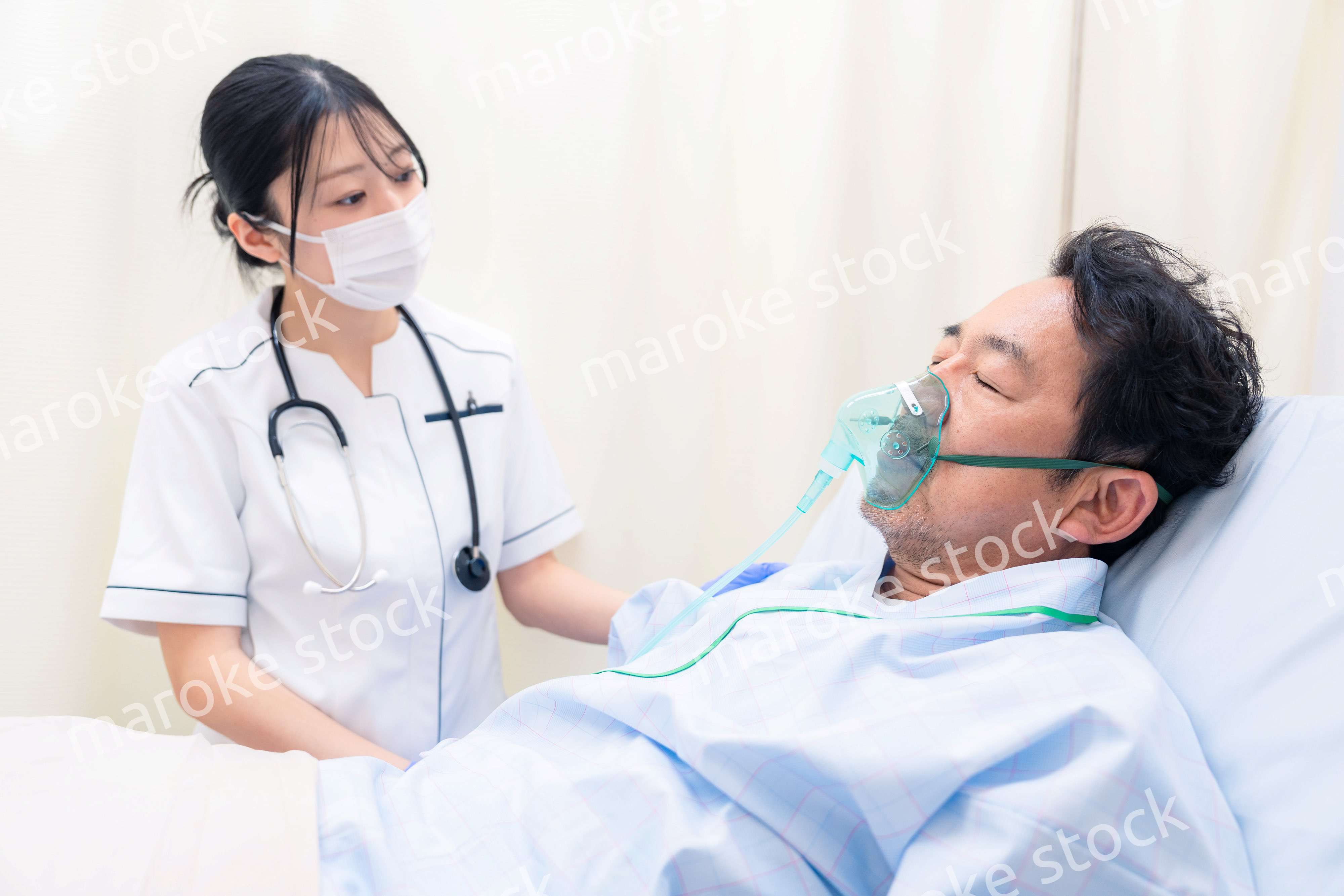 人工呼吸器をつけた患者のケアをする看護師の女性