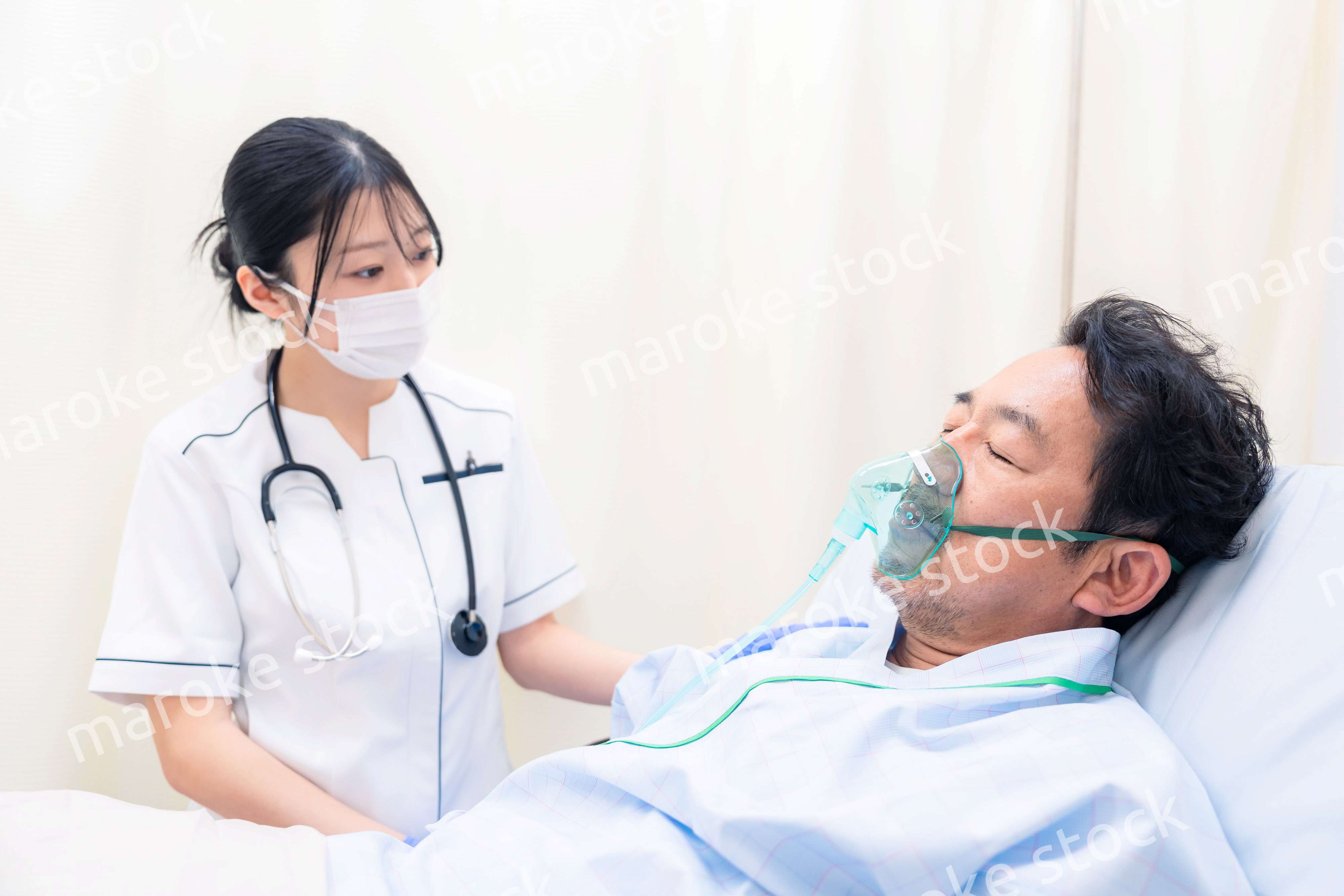 人工呼吸器をつけた患者のケアをする看護師の女性