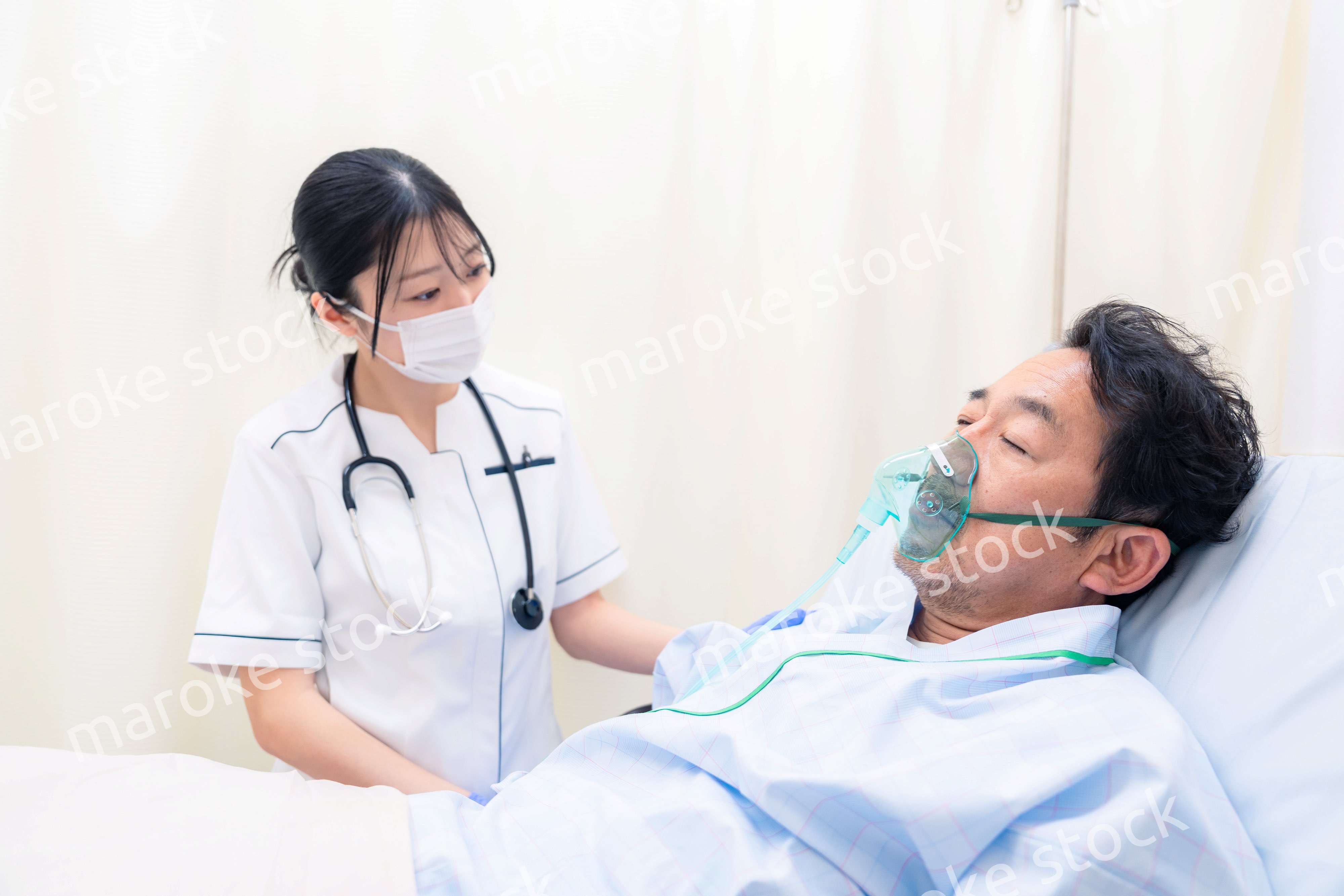 人工呼吸器をつけた患者のケアをする看護師の女性