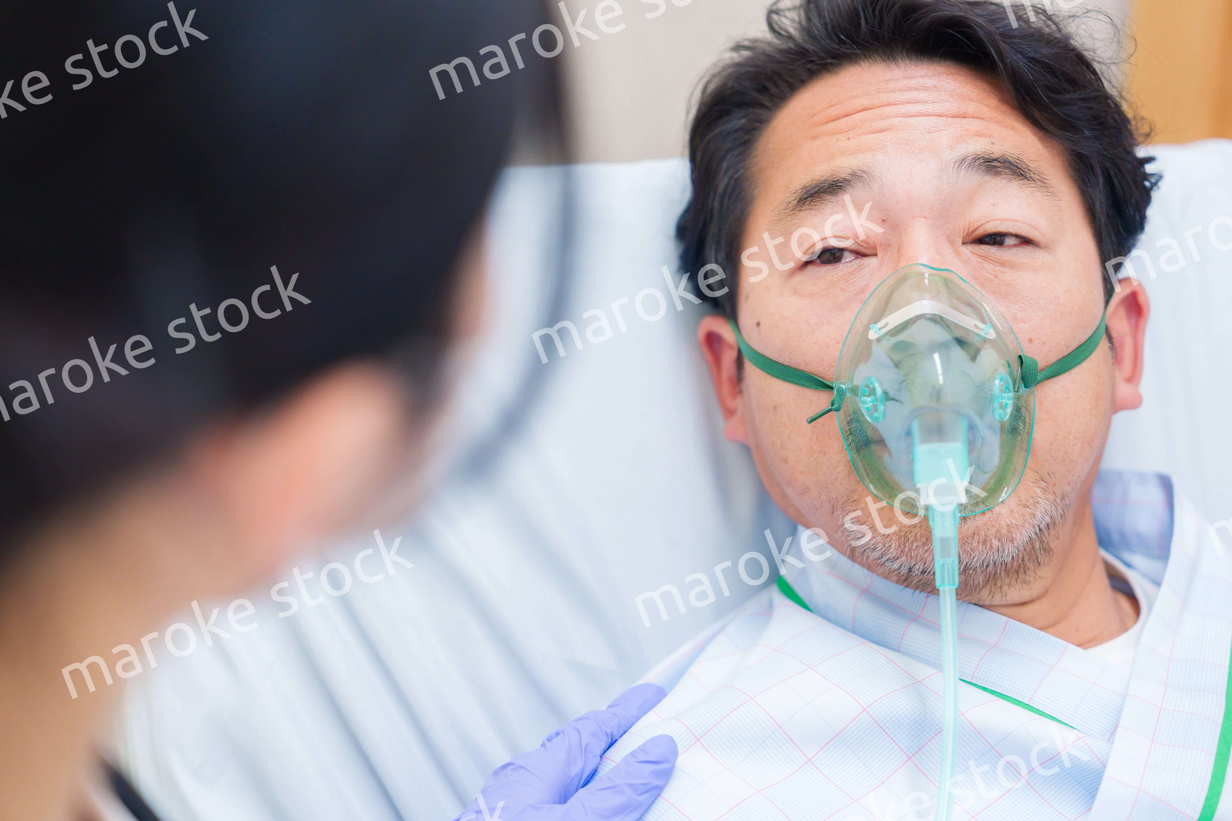 人工呼吸器をつけて話をする入院患者の男性