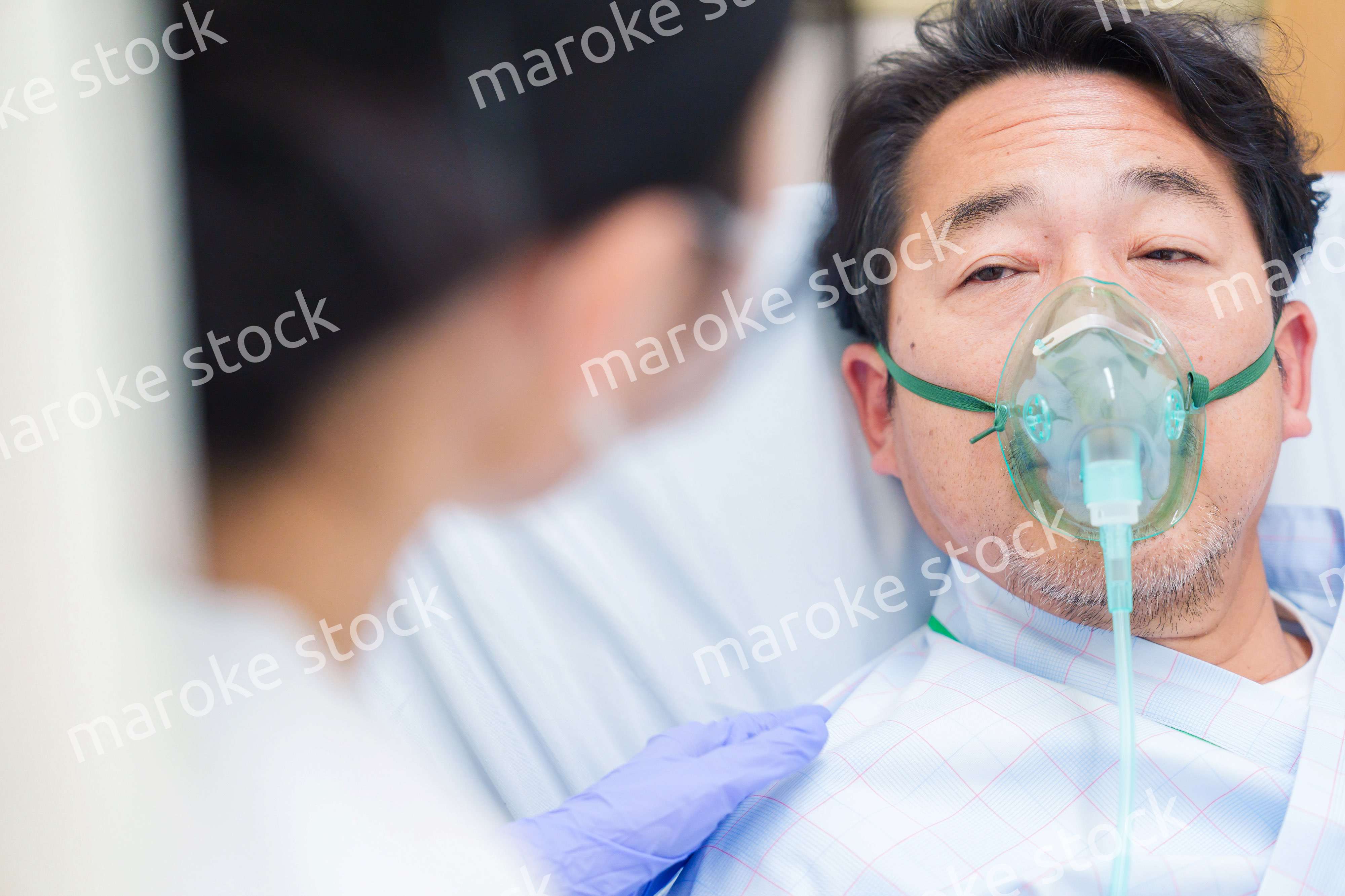 人工呼吸器をつけて話をする入院患者の男性