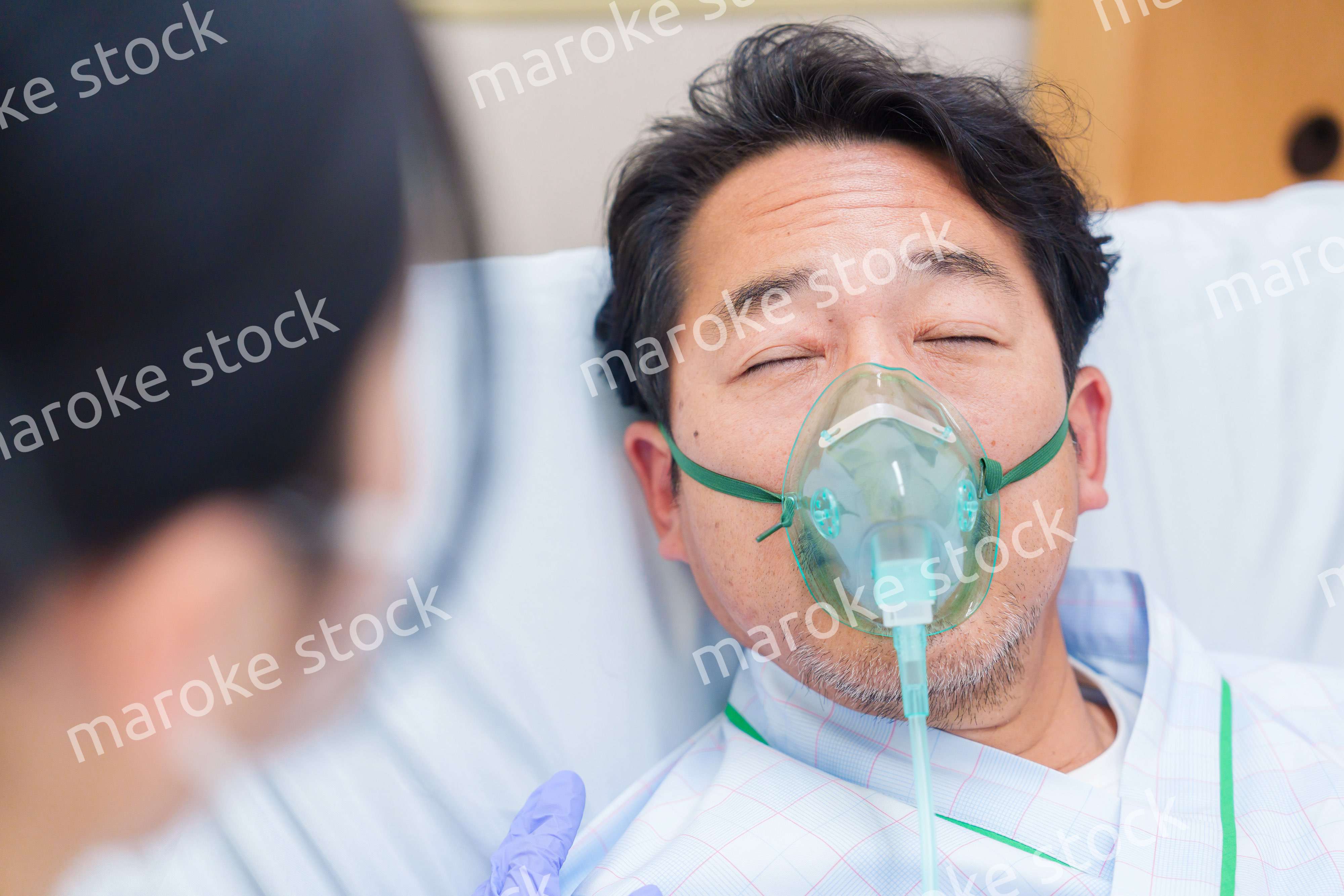 人工呼吸器をつけて話をする入院患者の男性