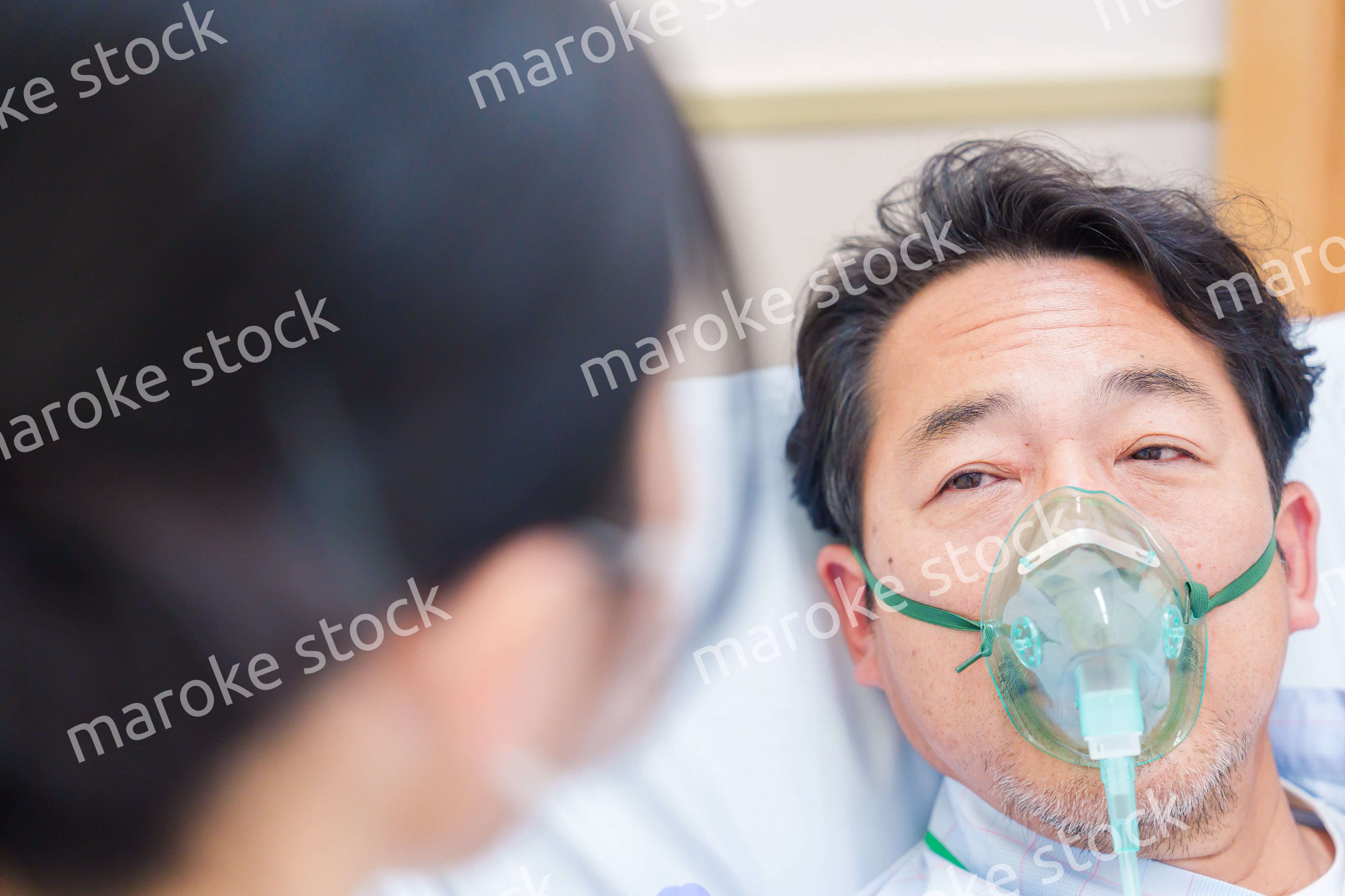 人工呼吸器をつけて話をする入院患者の男性