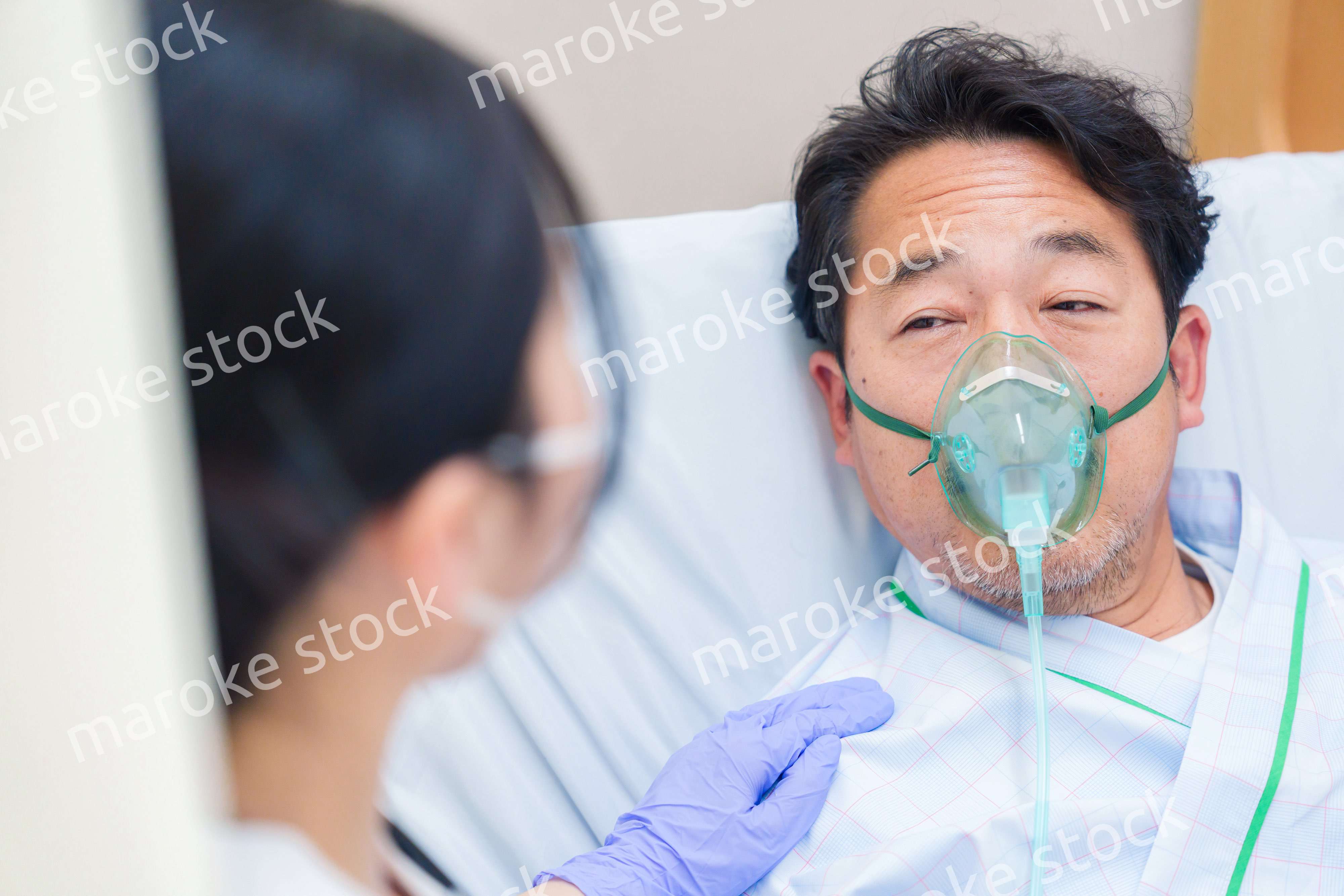 人工呼吸器をつけて話をする入院患者の男性