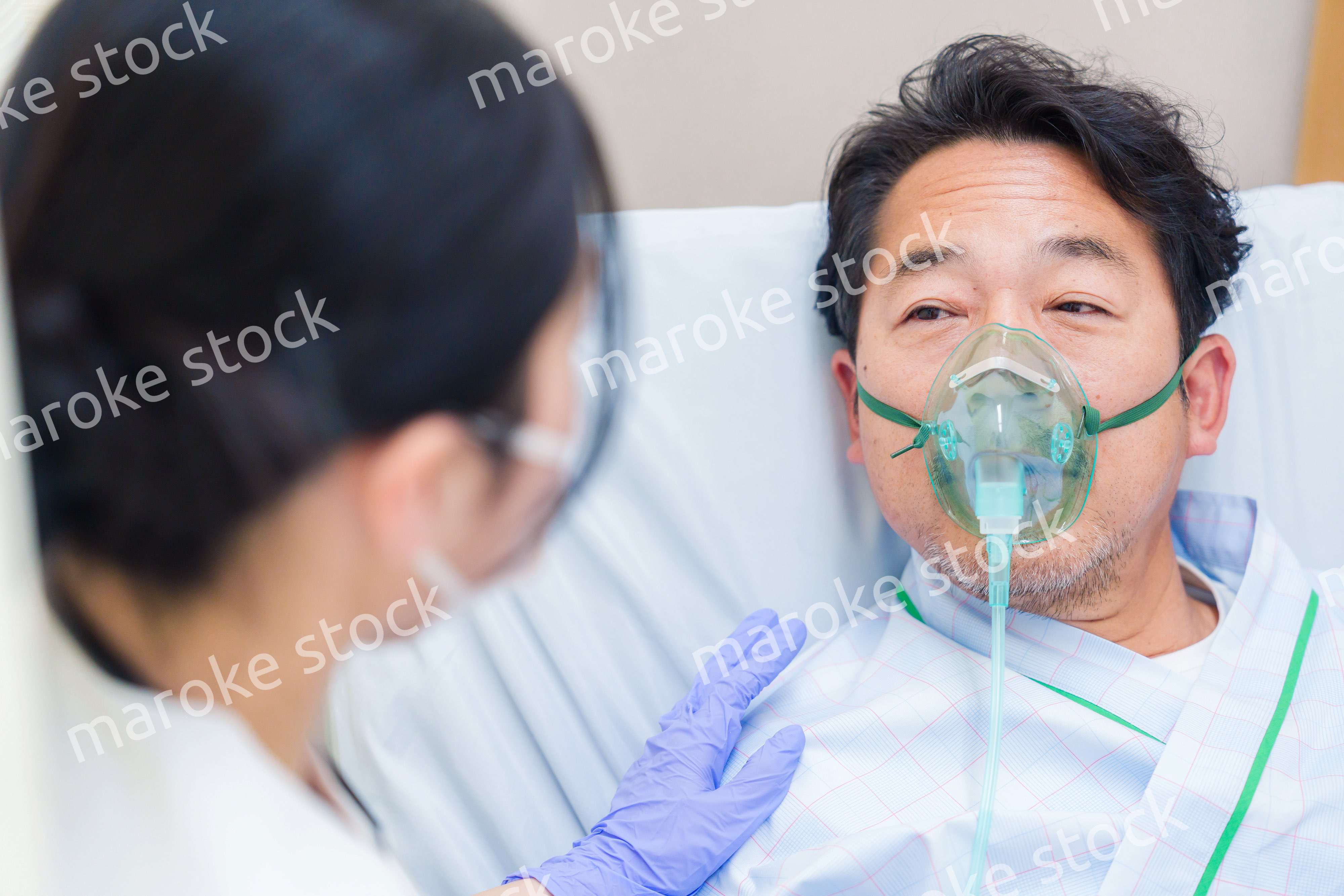 人工呼吸器をつけて話をする入院患者の男性