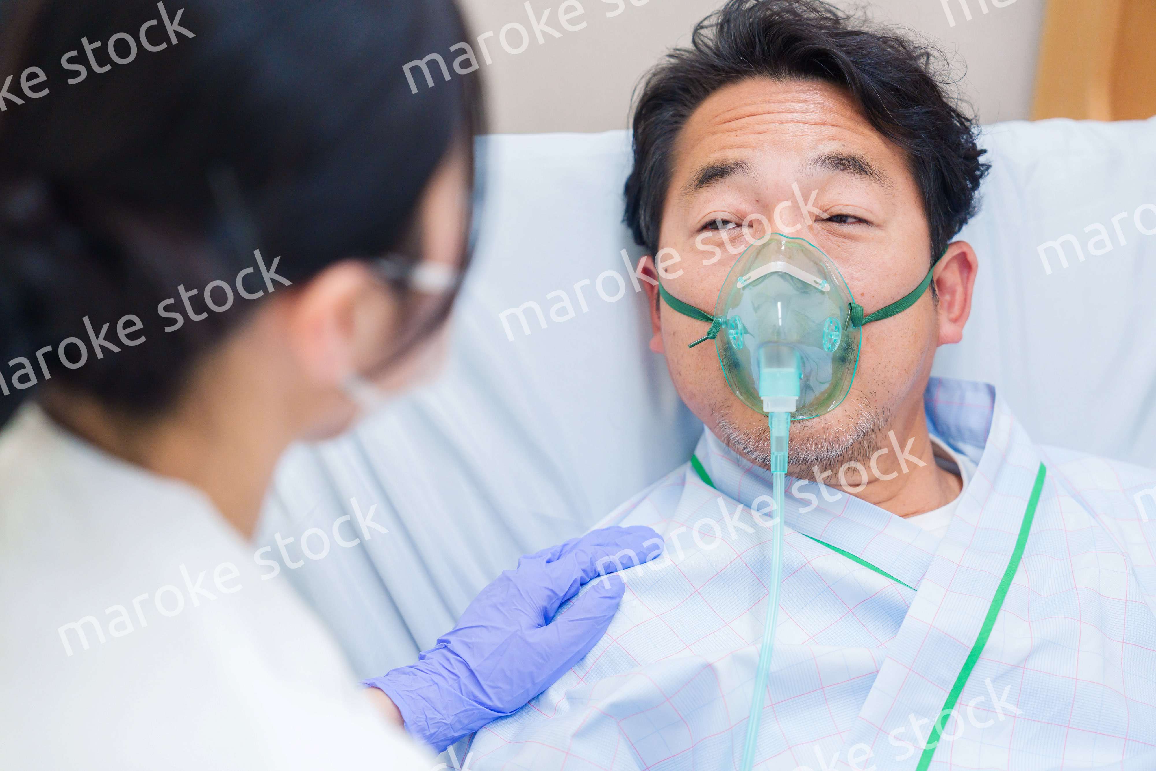 人工呼吸器をつけて話をする入院患者の男性