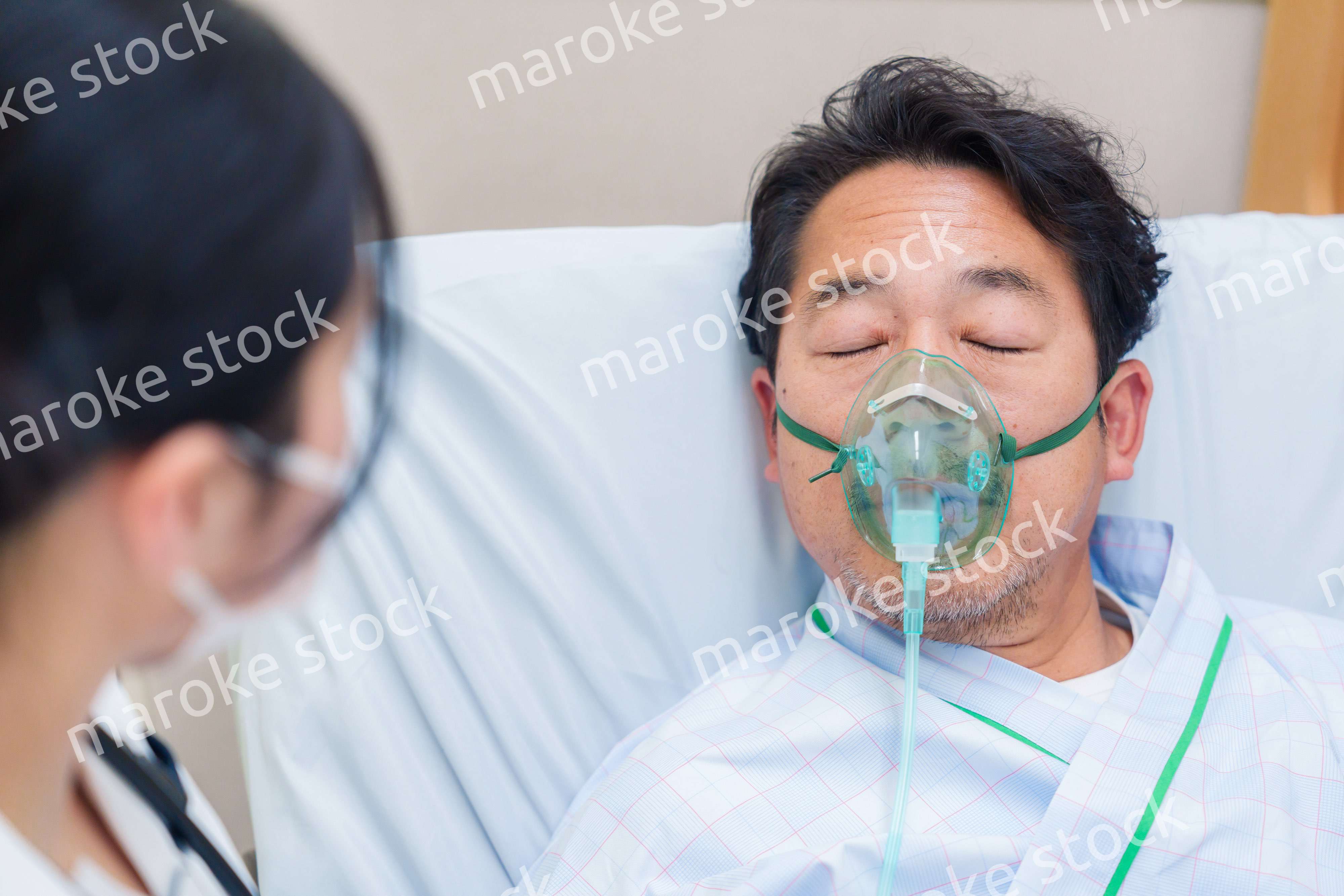 人工呼吸器をつけて話をする入院患者の男性