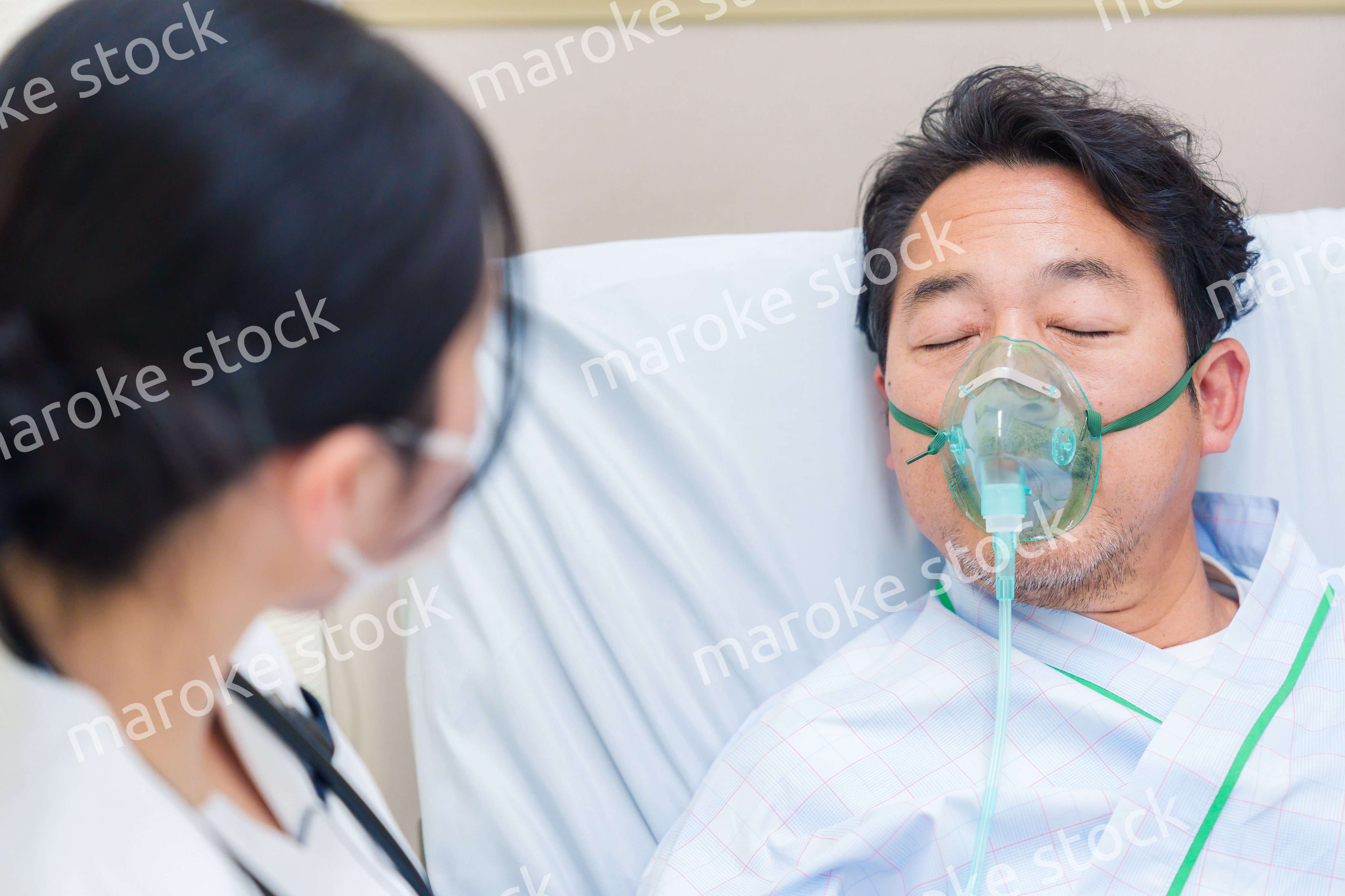 人工呼吸器をつけて話をする入院患者の男性