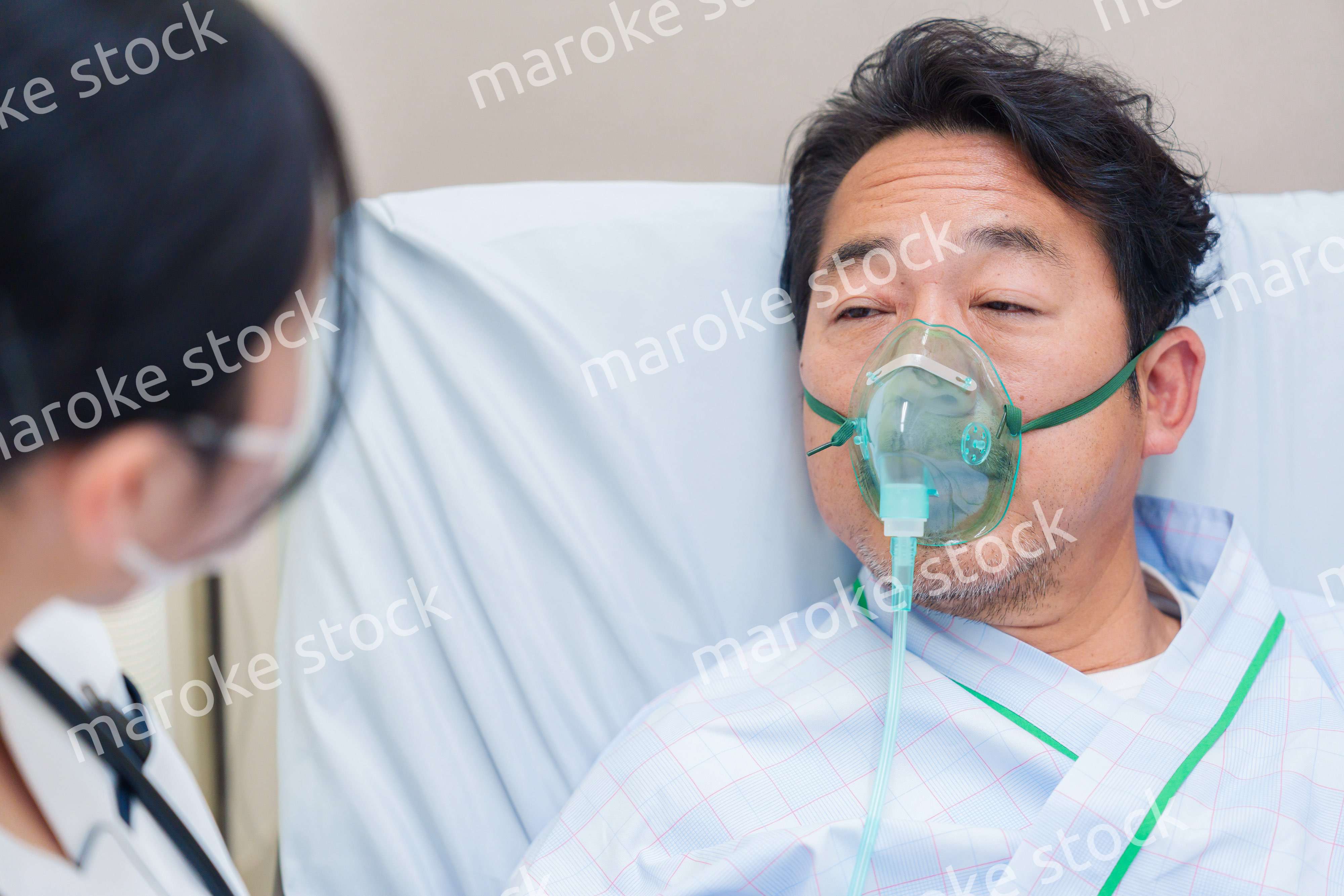 人工呼吸器をつけて話をする入院患者の男性