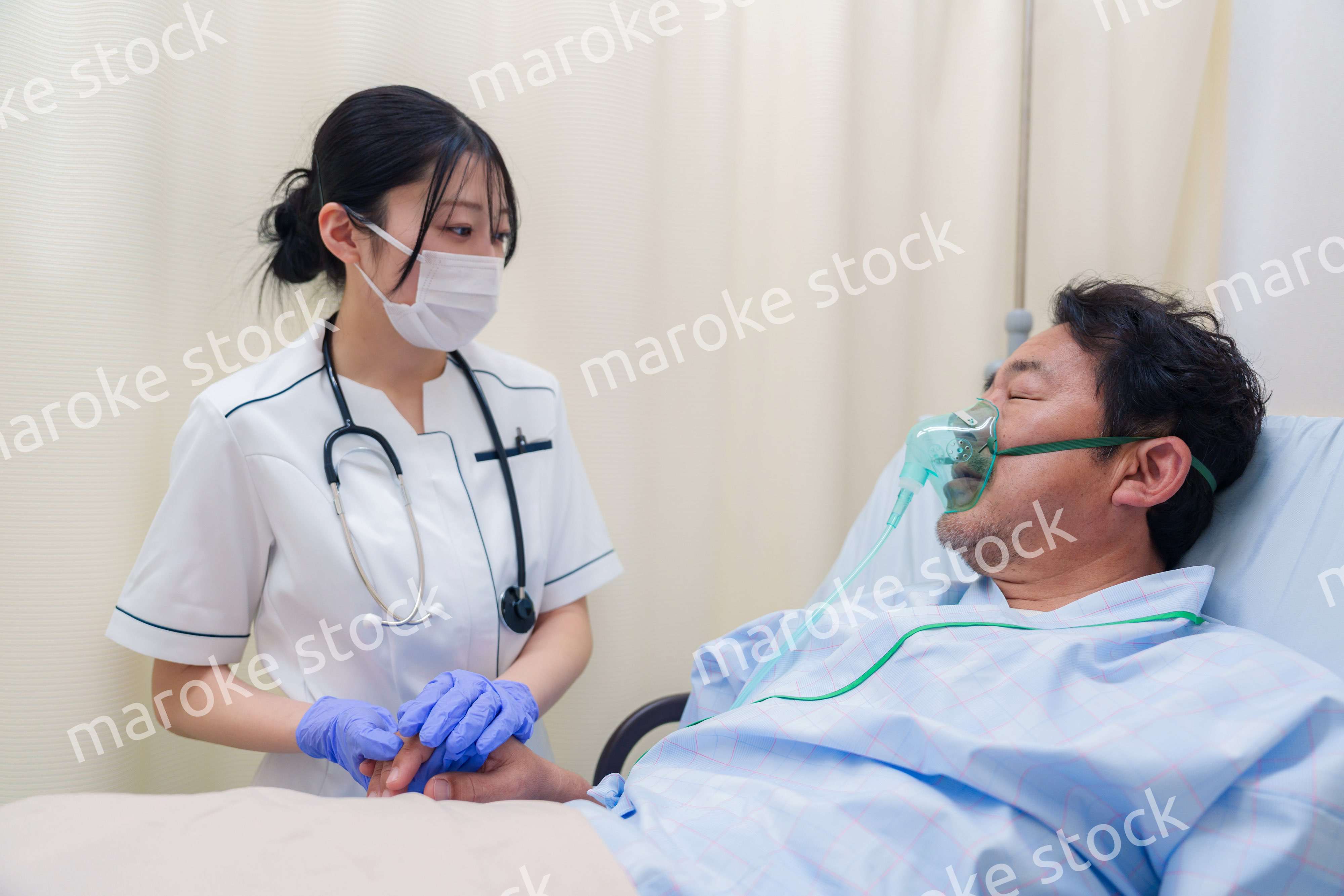 看護師の手を握る入院患者の男性