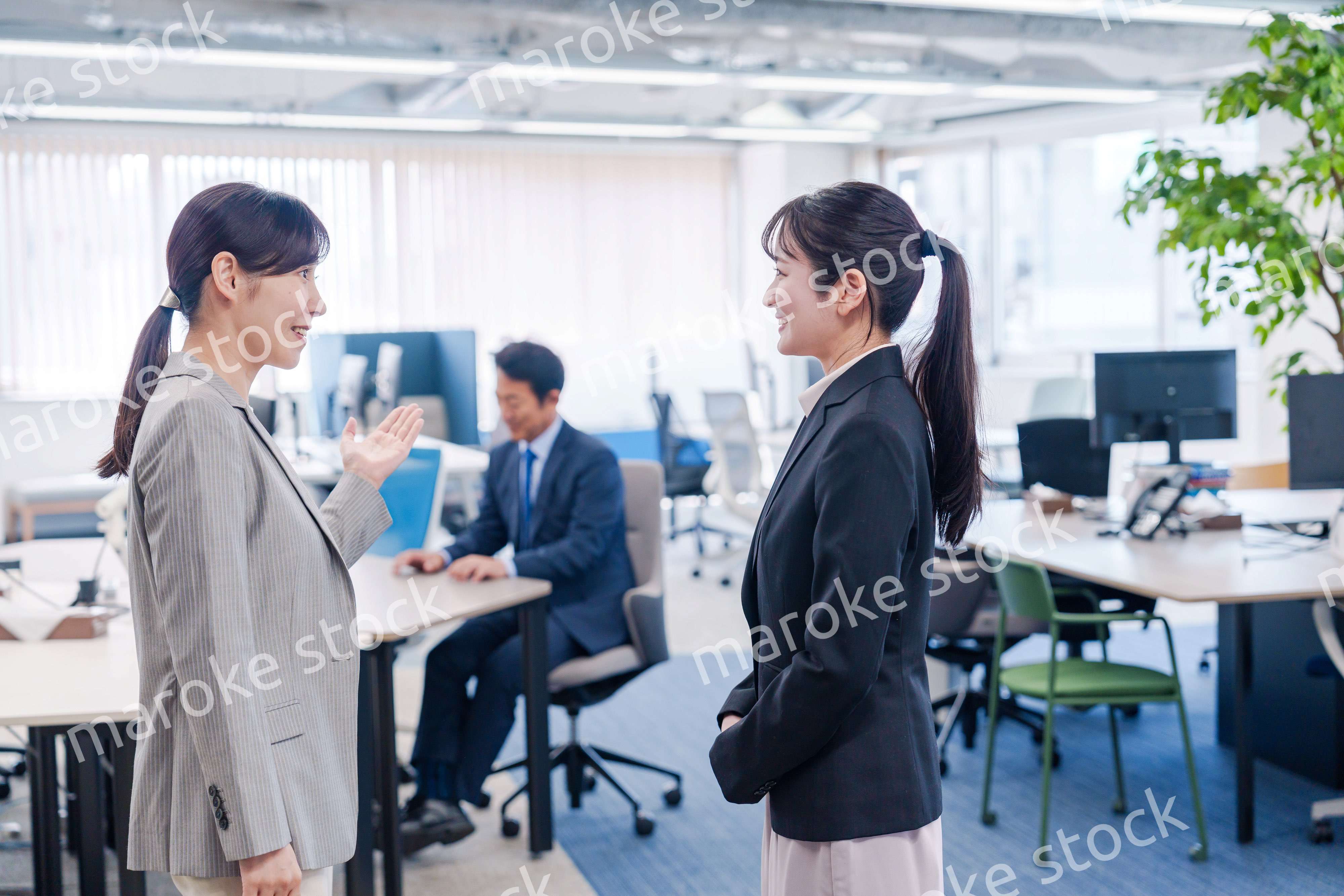 先輩社員にオフィスを案内してもらうフレッシュな女性