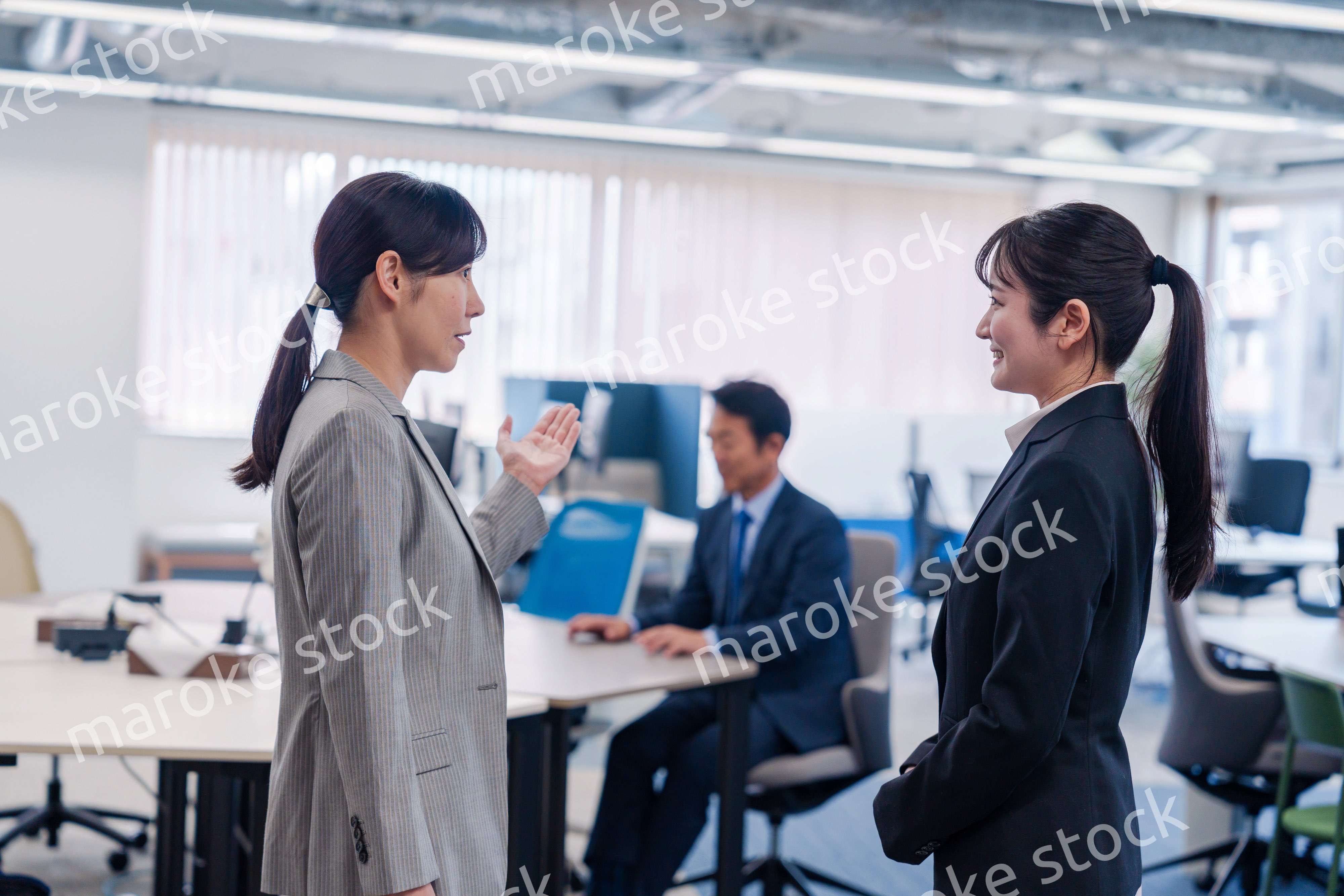 先輩社員にオフィスを案内してもらうフレッシュな女性