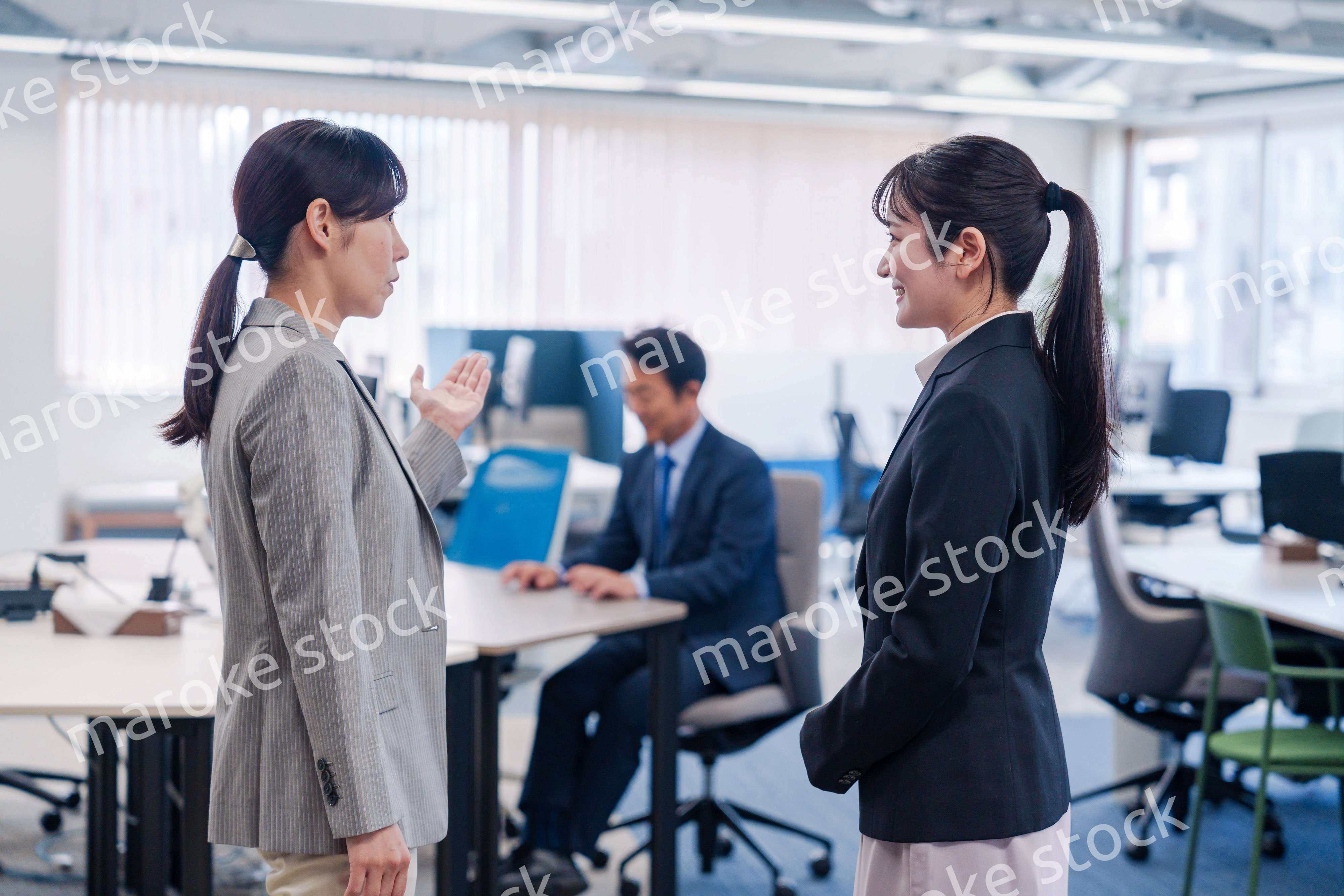 先輩社員にオフィスを案内してもらうフレッシュな女性