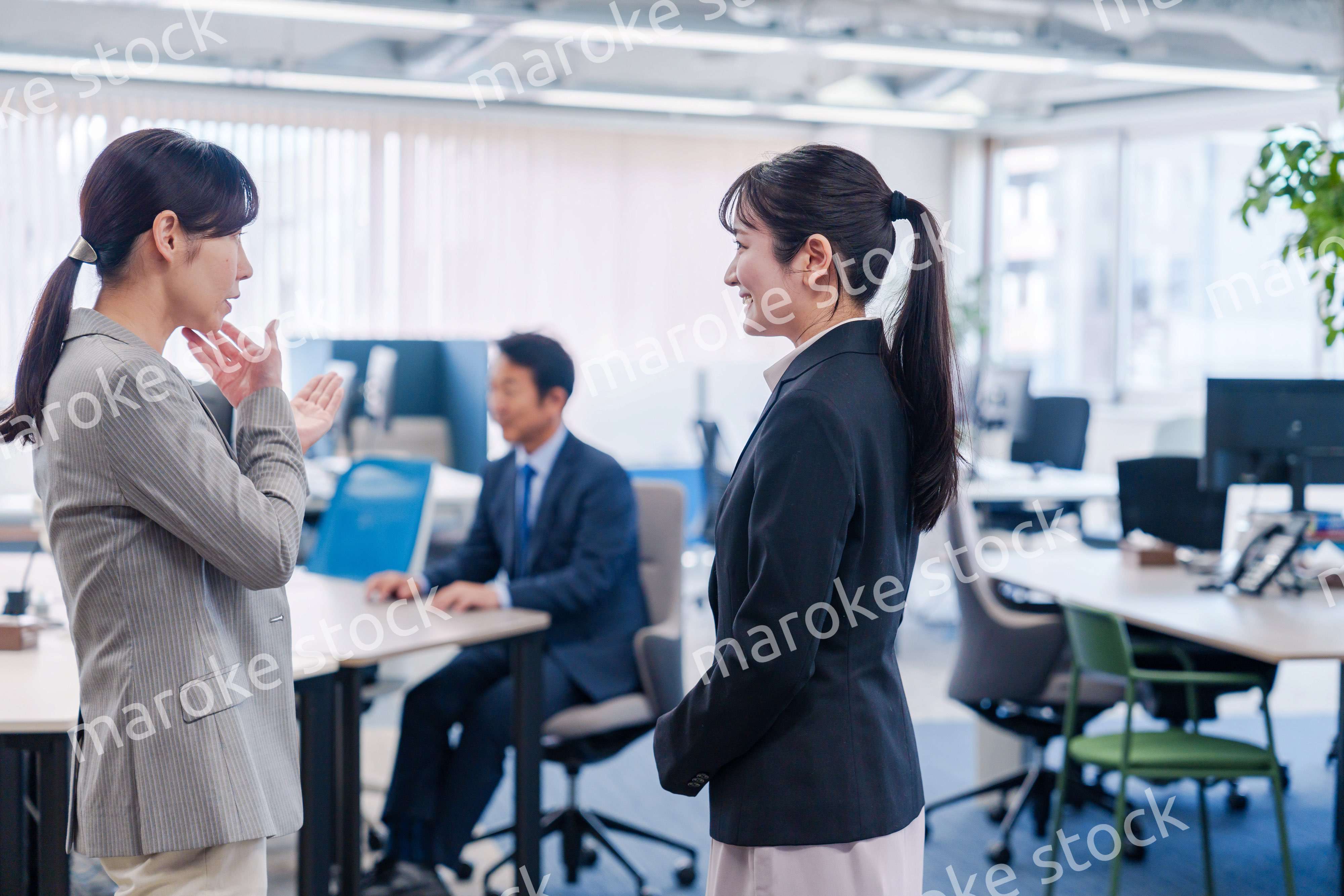 先輩社員にオフィスを案内してもらうフレッシュな女性