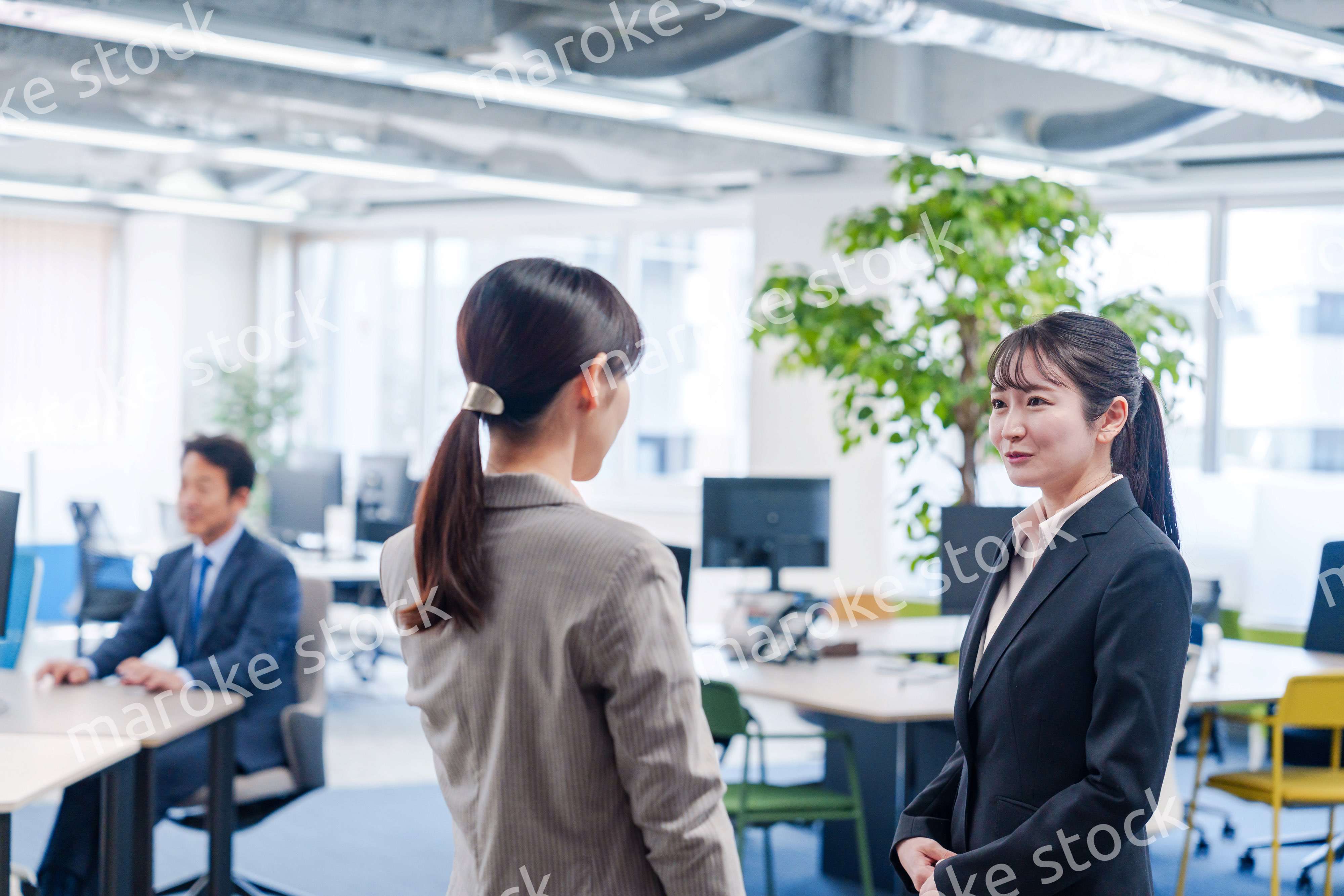 先輩社員にオフィスを案内してもらうフレッシュな女性