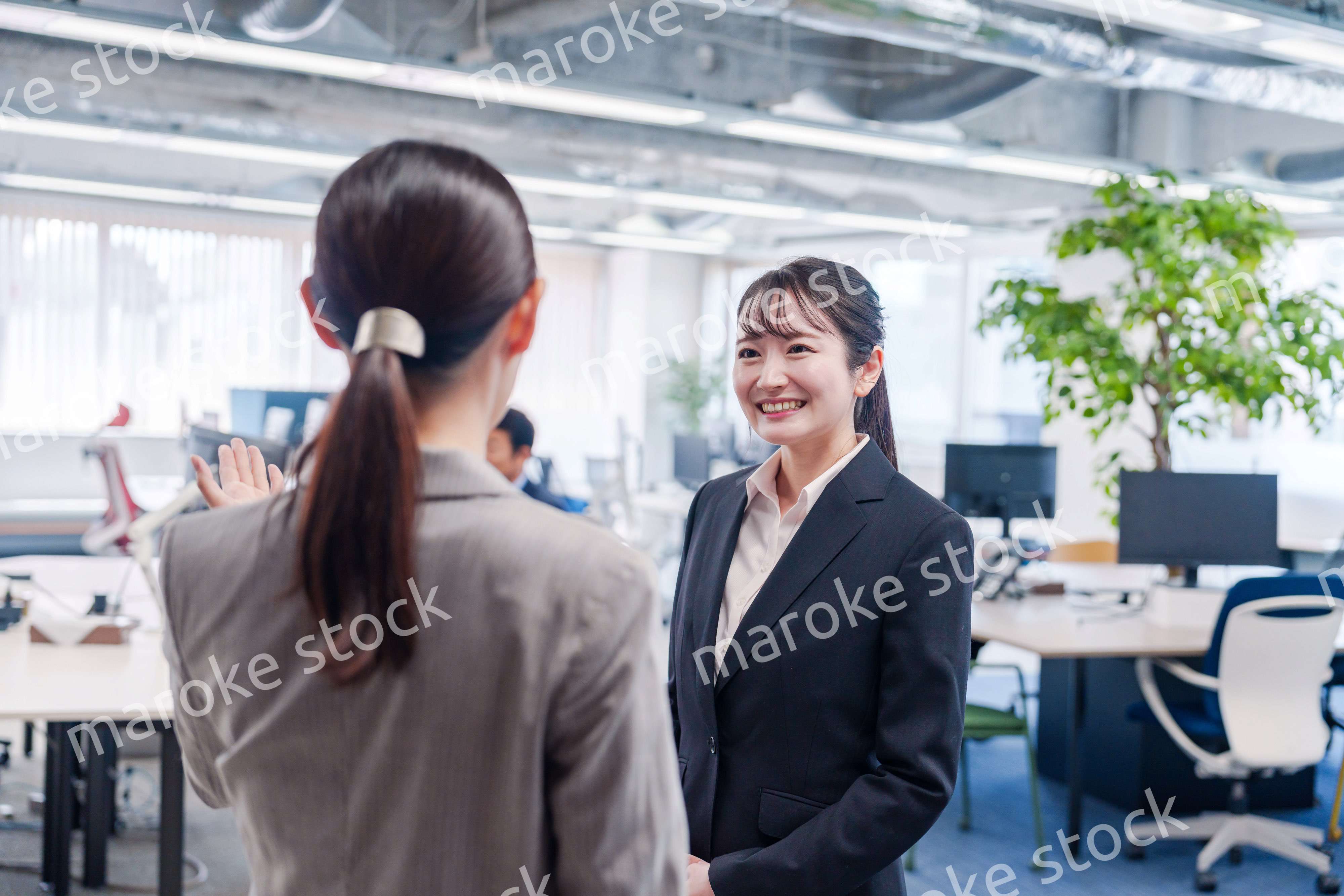 先輩社員にオフィスを案内してもらうフレッシュな女性