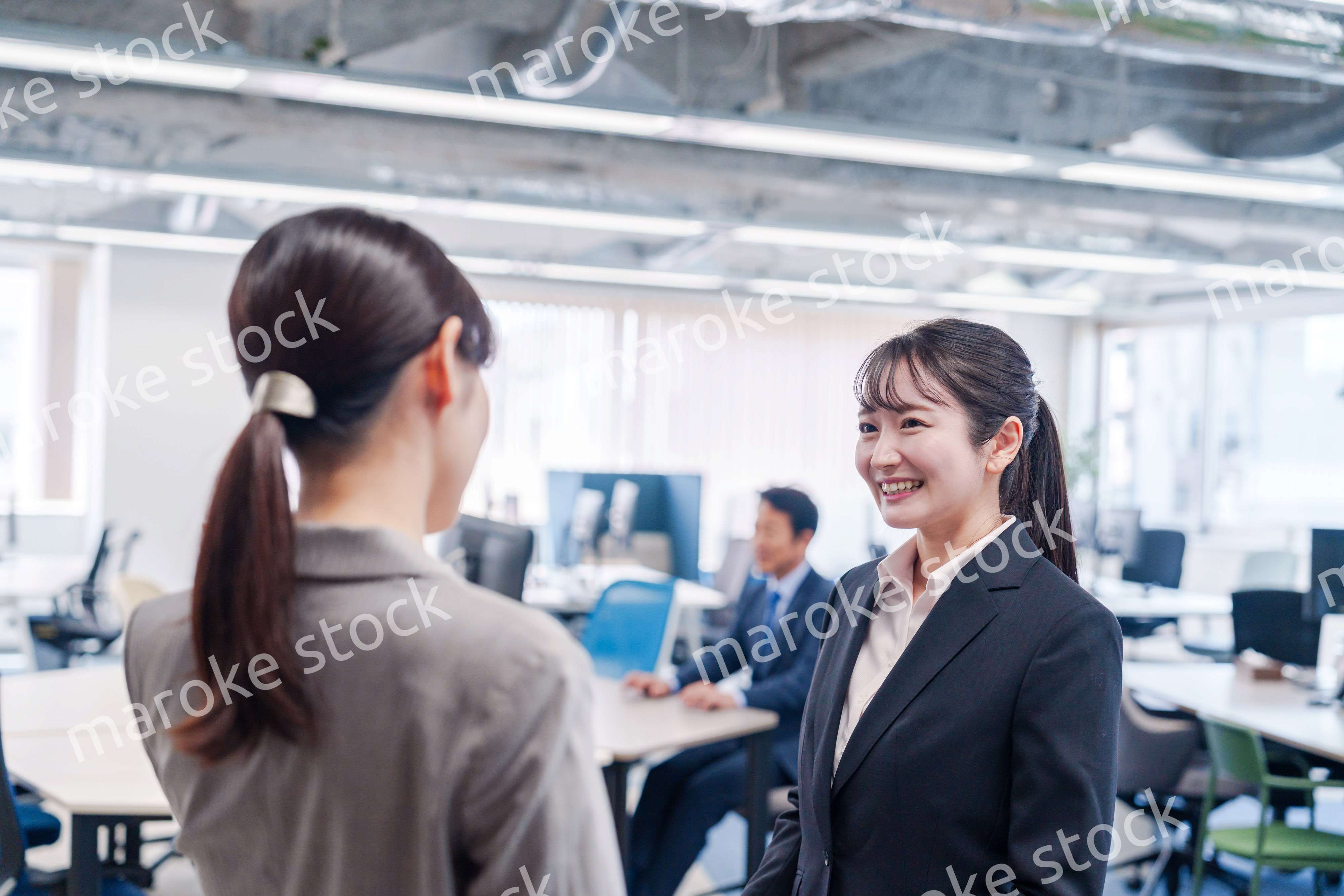 先輩社員にオフィスを案内してもらうフレッシュな女性