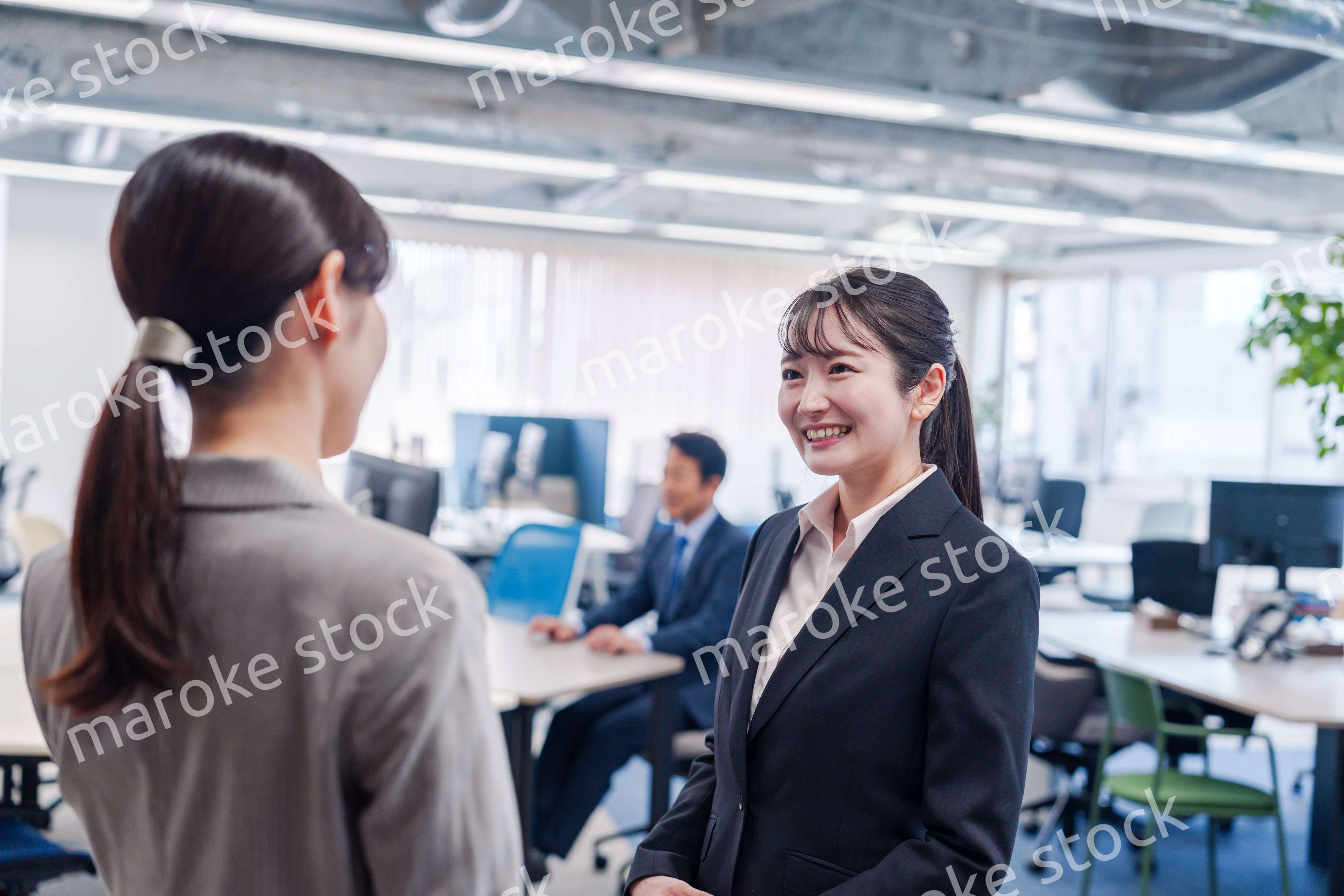 先輩社員にオフィスを案内してもらうフレッシュな女性