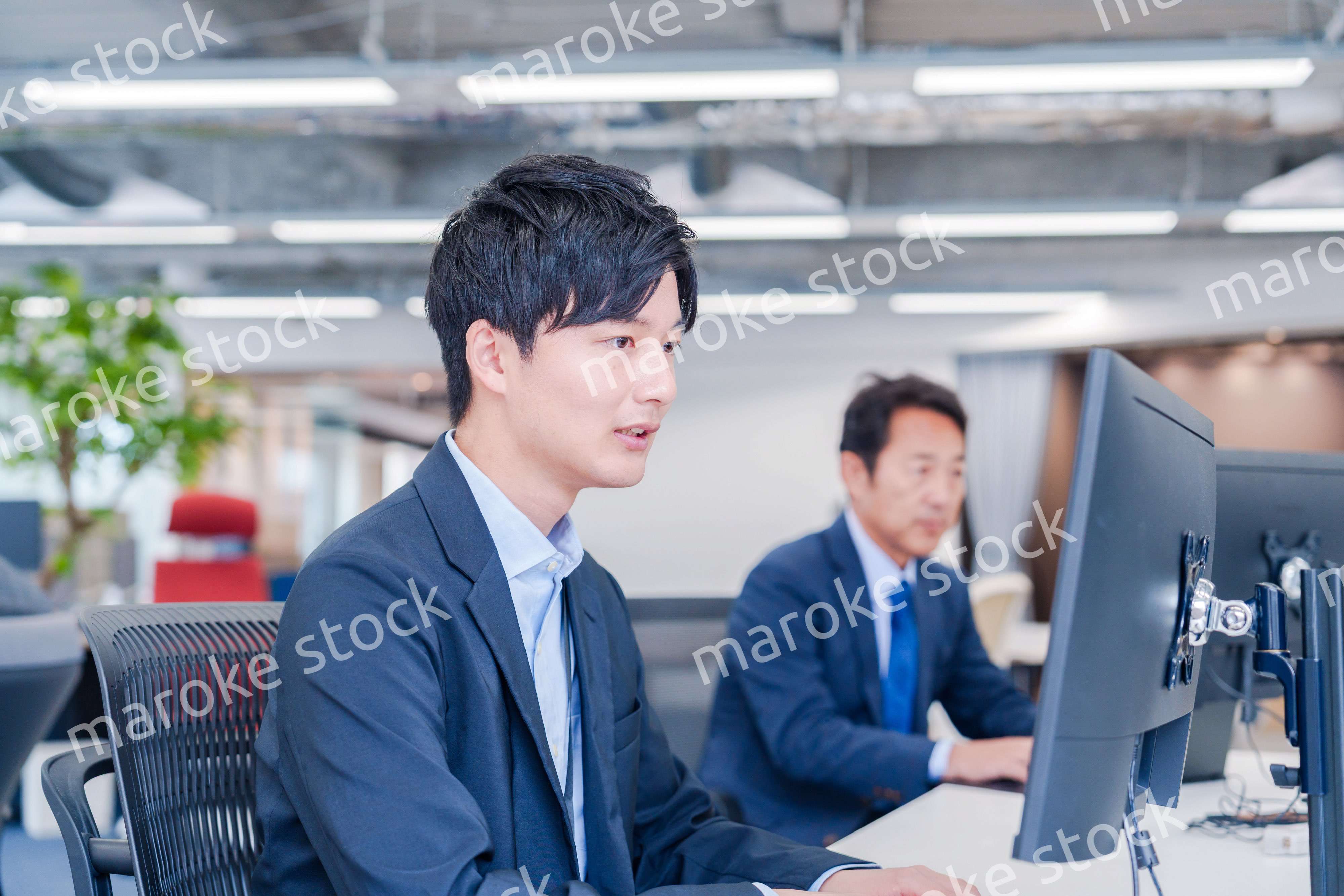 オフィスでモニタに向かって働くビジネスマン