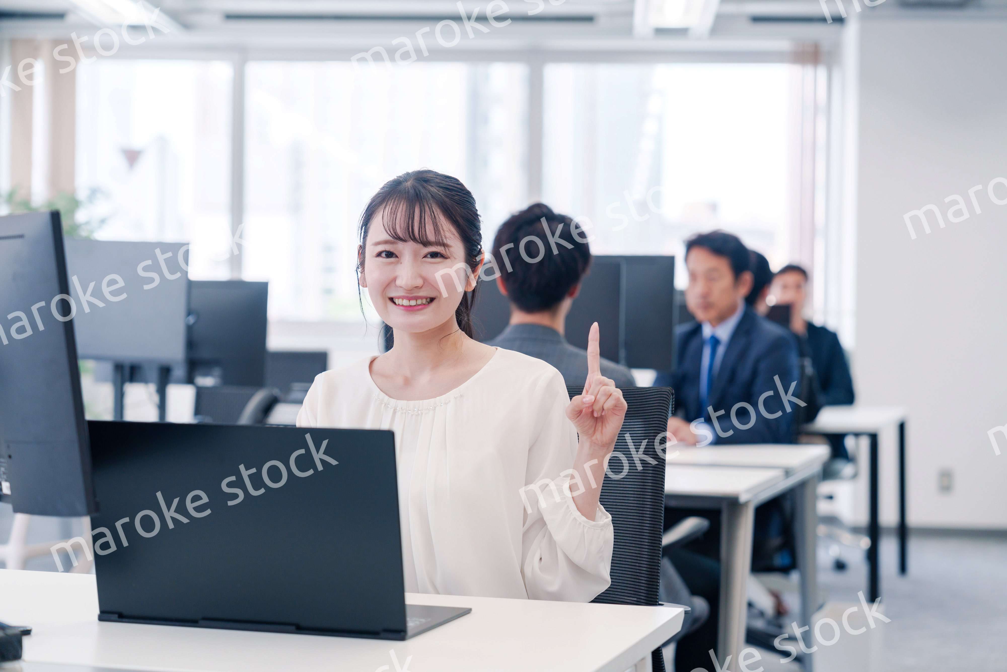 オフィスでデスクワークをしながら指を指す若いビジネスウーマン