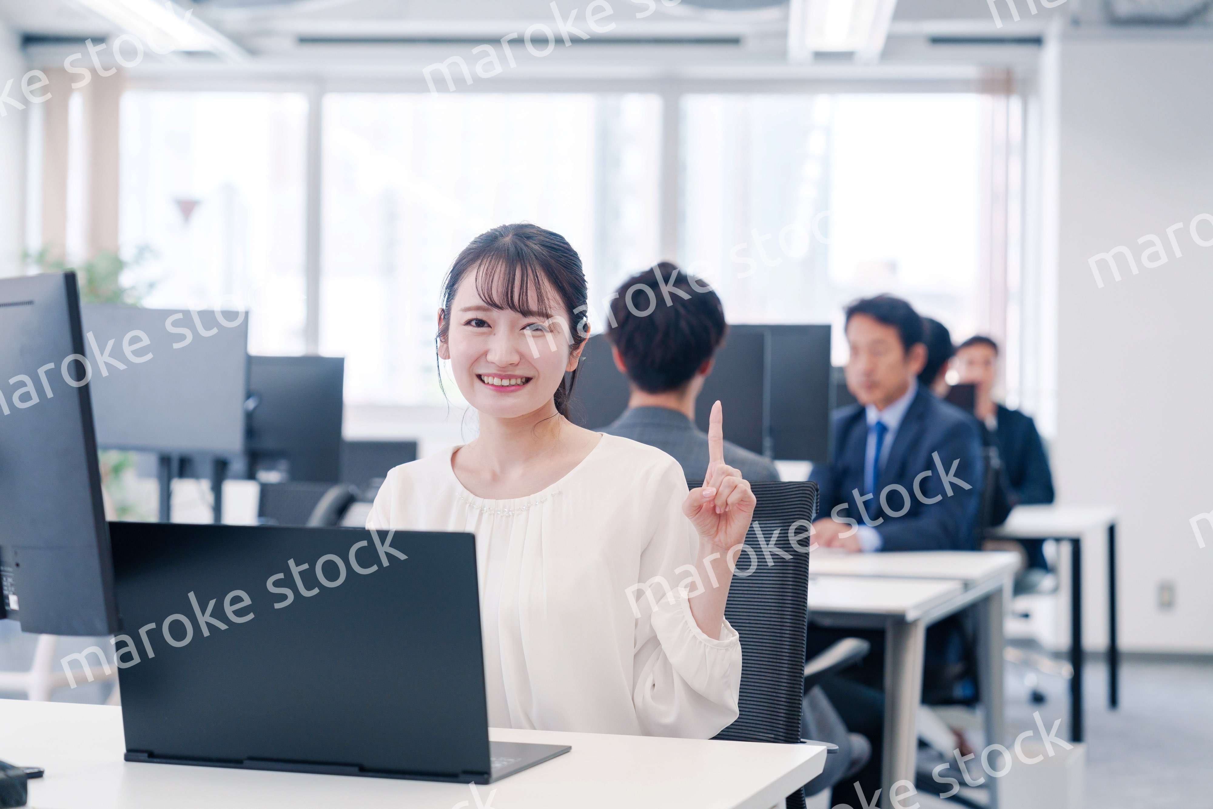 オフィスでデスクワークをしながら指を指す若いビジネスウーマン