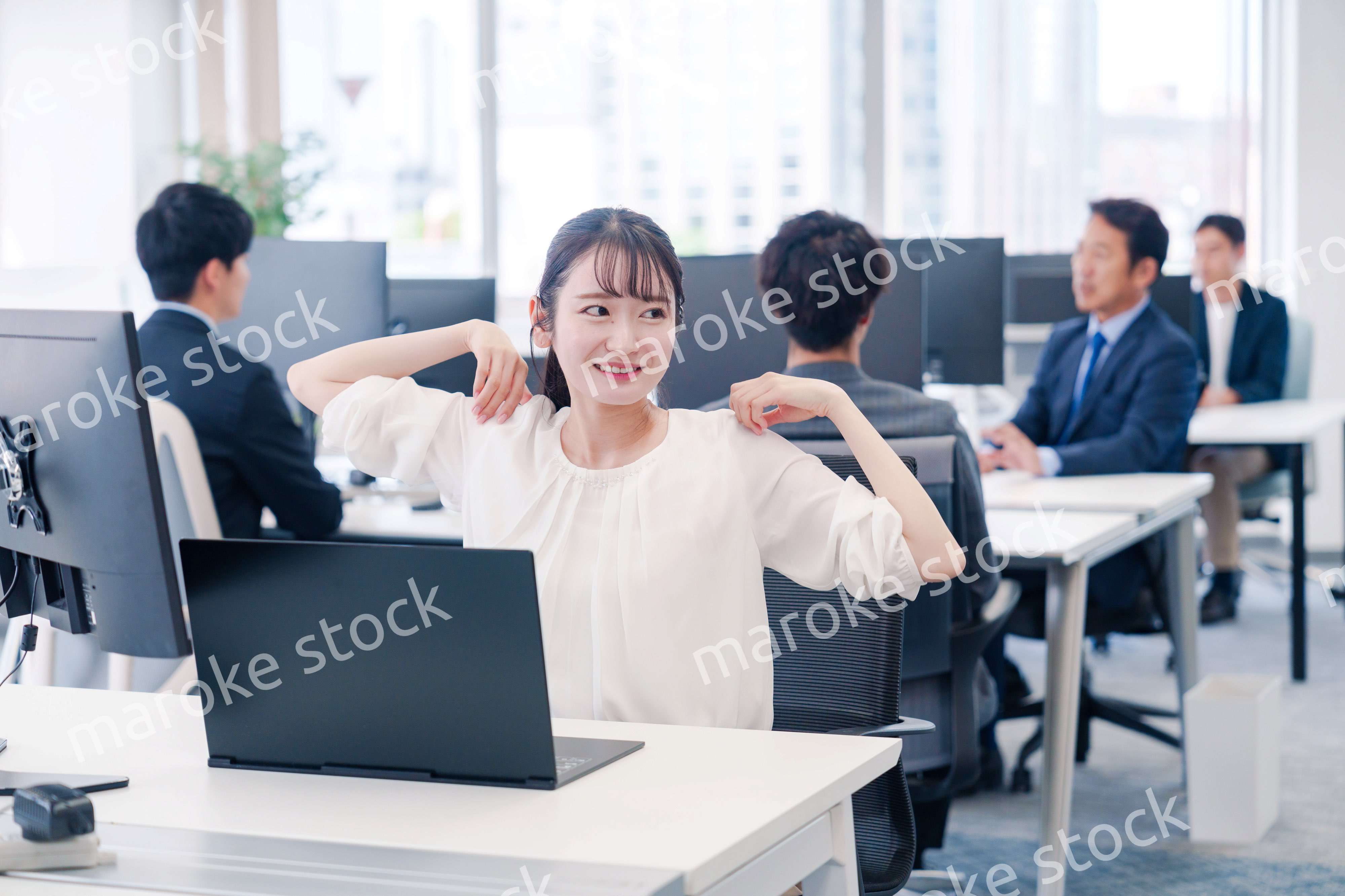 オフィスで伸びをしてリフレッシュするビジネスウーマン