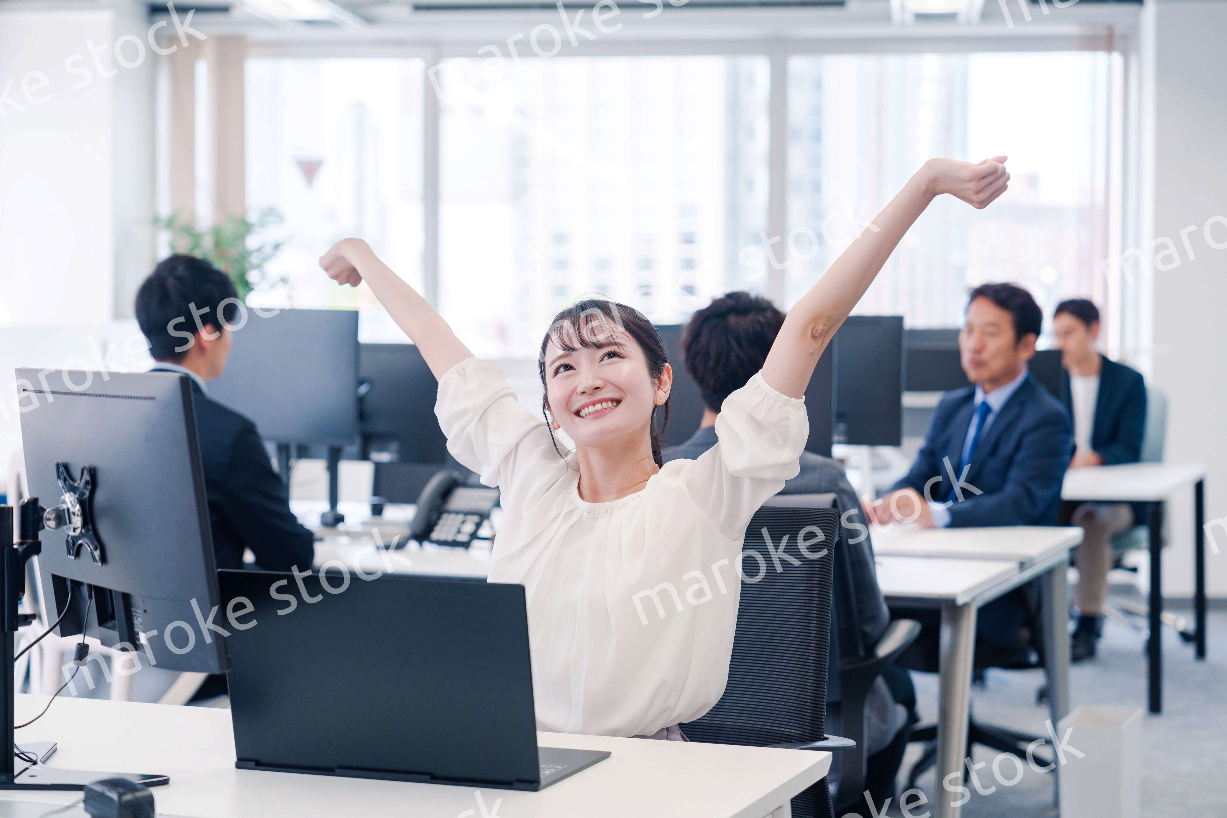 オフィスで伸びをしてリフレッシュするビジネスウーマン