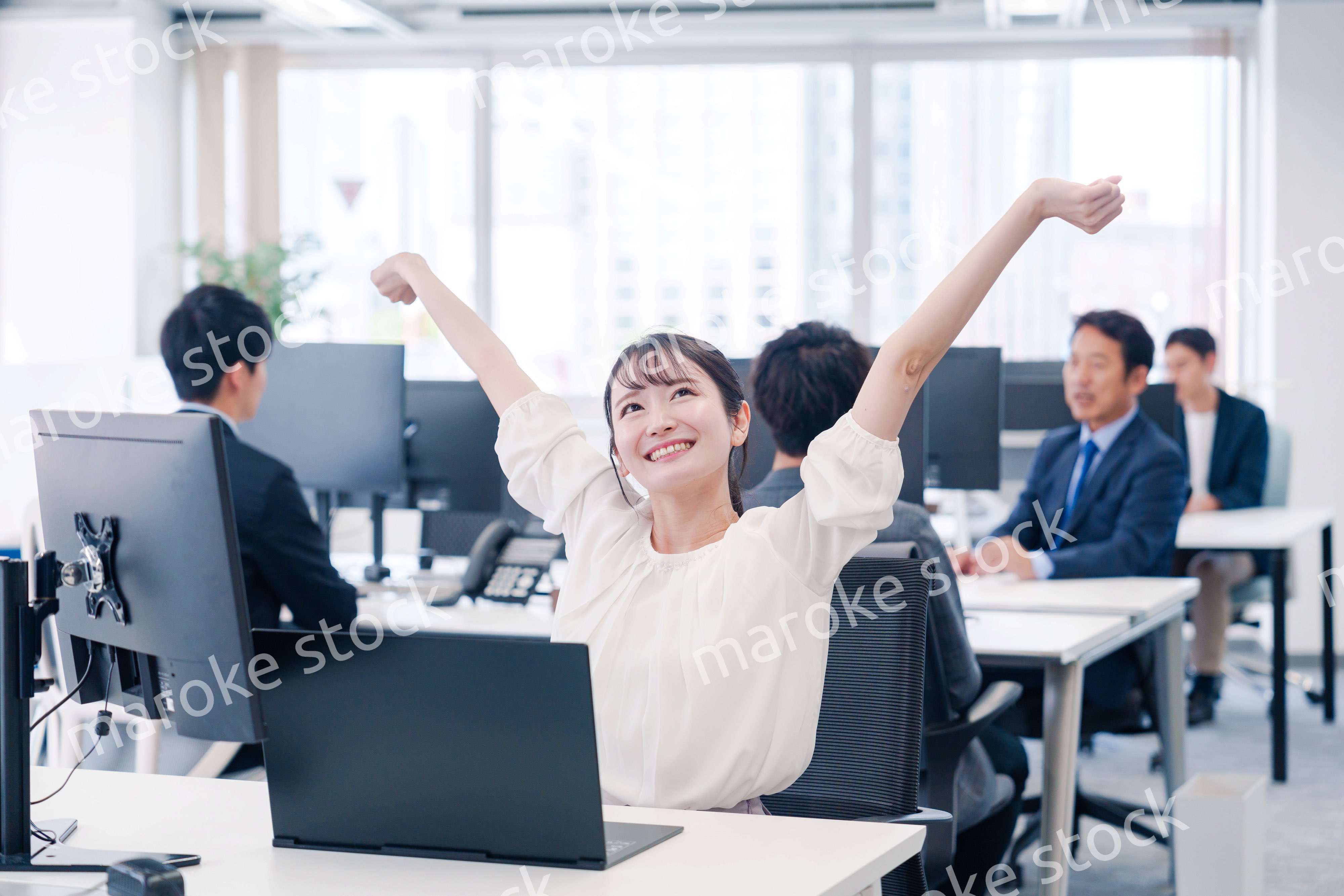 オフィスで伸びをしてリフレッシュするビジネスウーマン