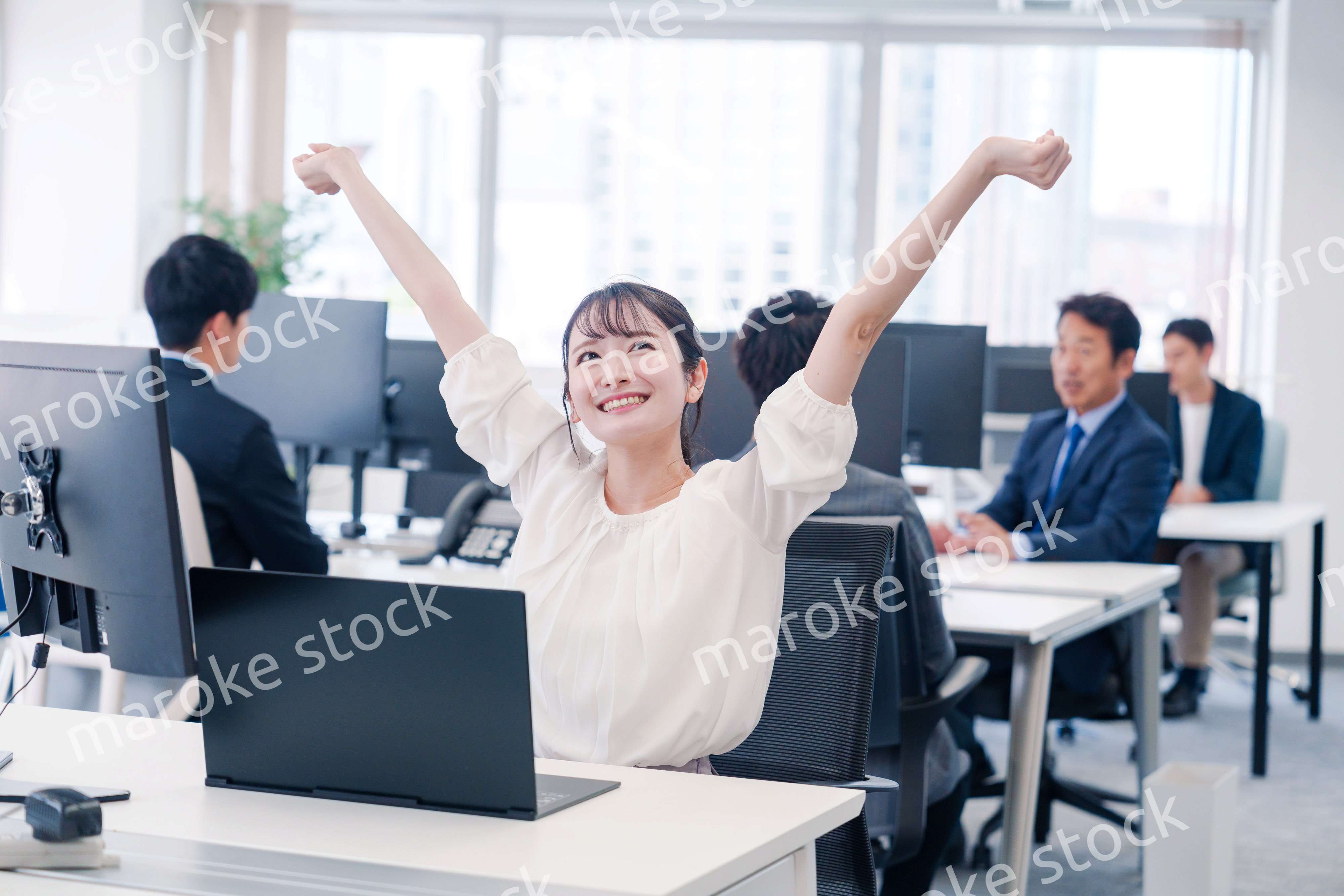 オフィスで伸びをしてリフレッシュするビジネスウーマン