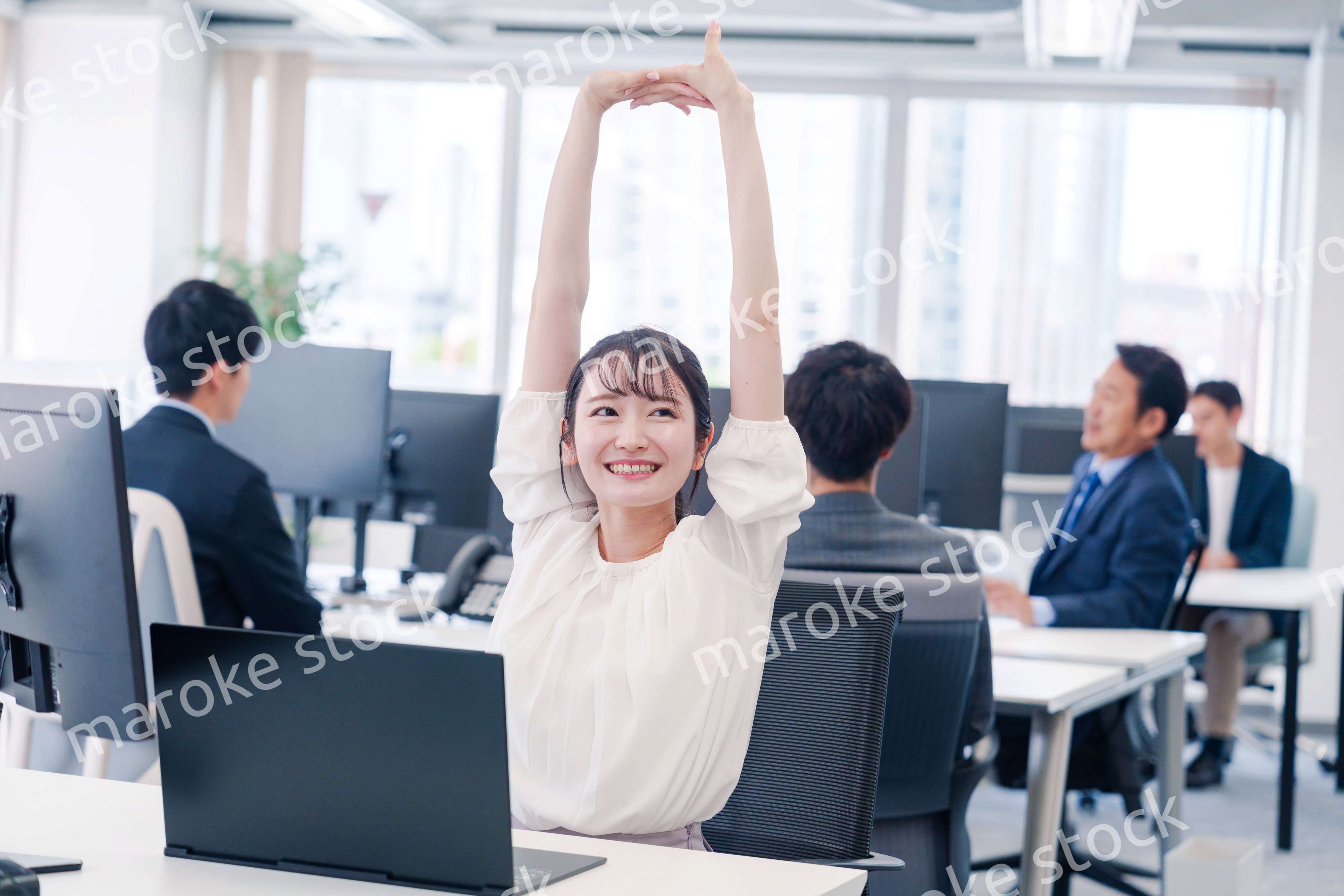 オフィスで伸びをしてリフレッシュするビジネスウーマン