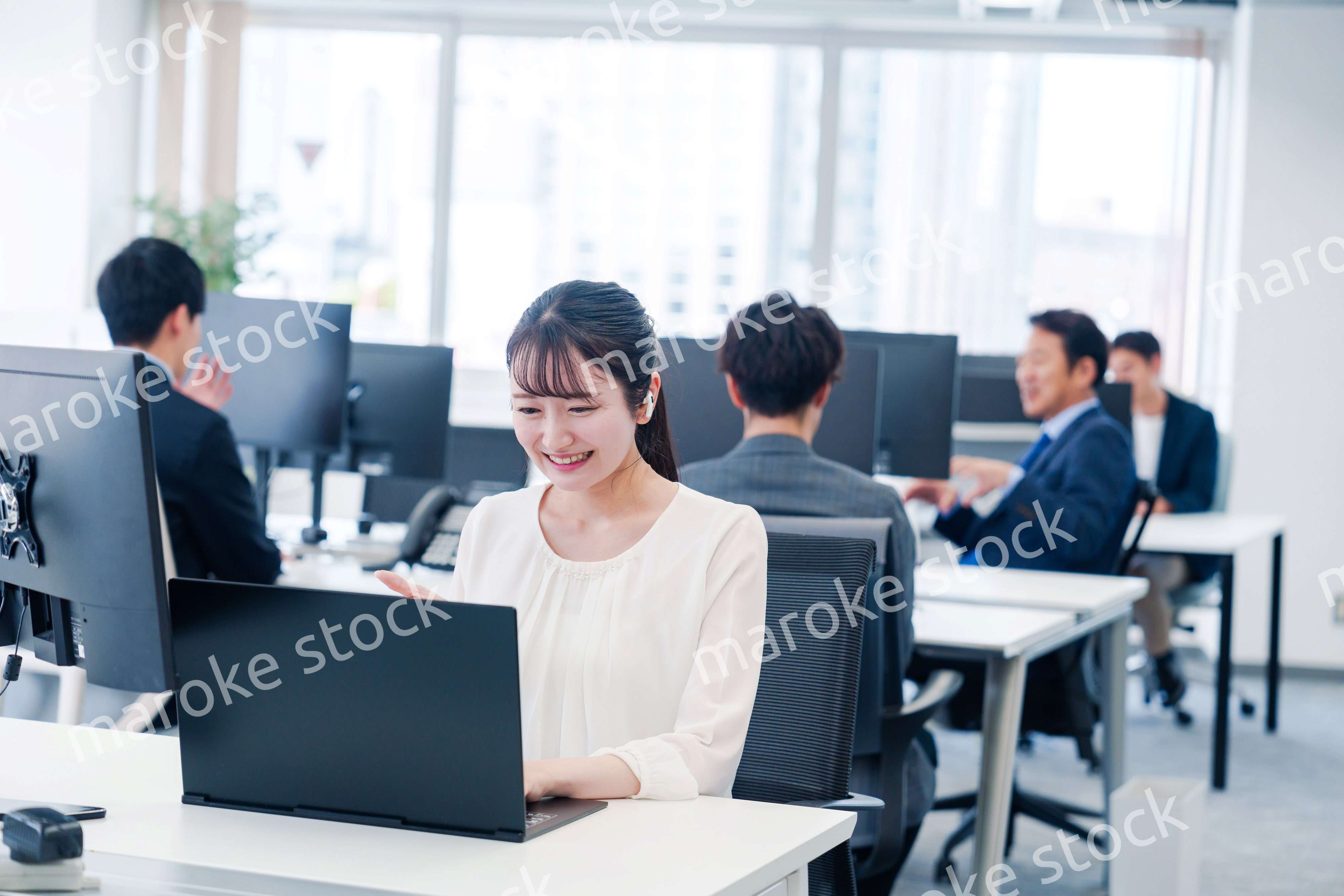 ワイヤレスイヤホンを使いオフィスでリモート会議をする女性