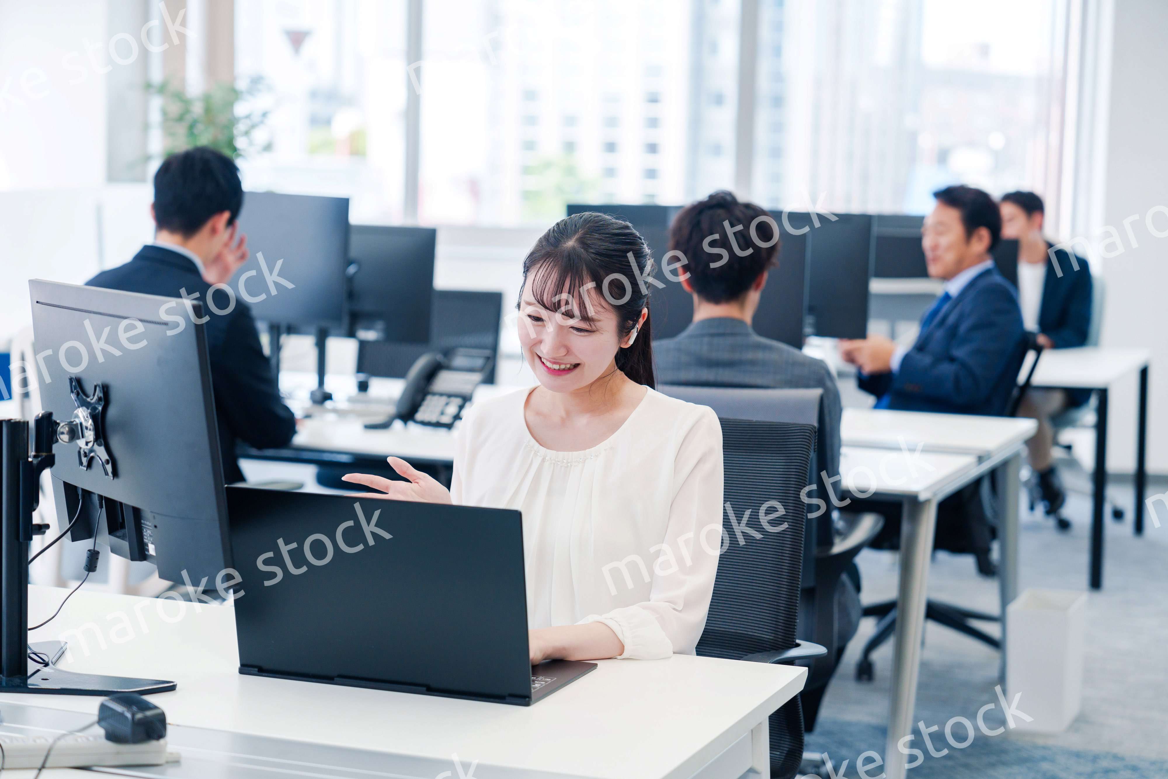 ワイヤレスイヤホンを使いオフィスでリモート会議をする女性