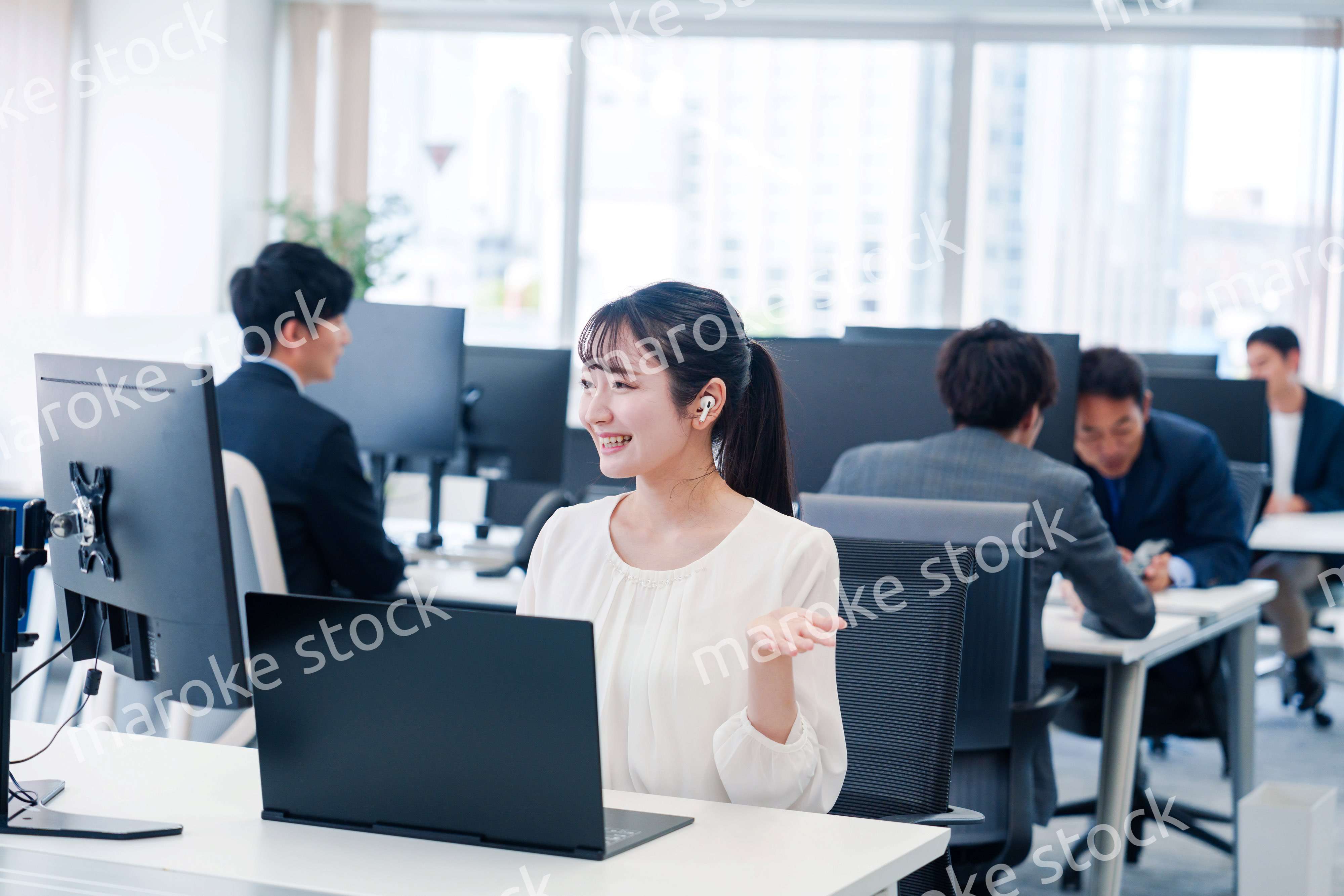 ワイヤレスイヤホンを使いオフィスでリモート会議をする女性