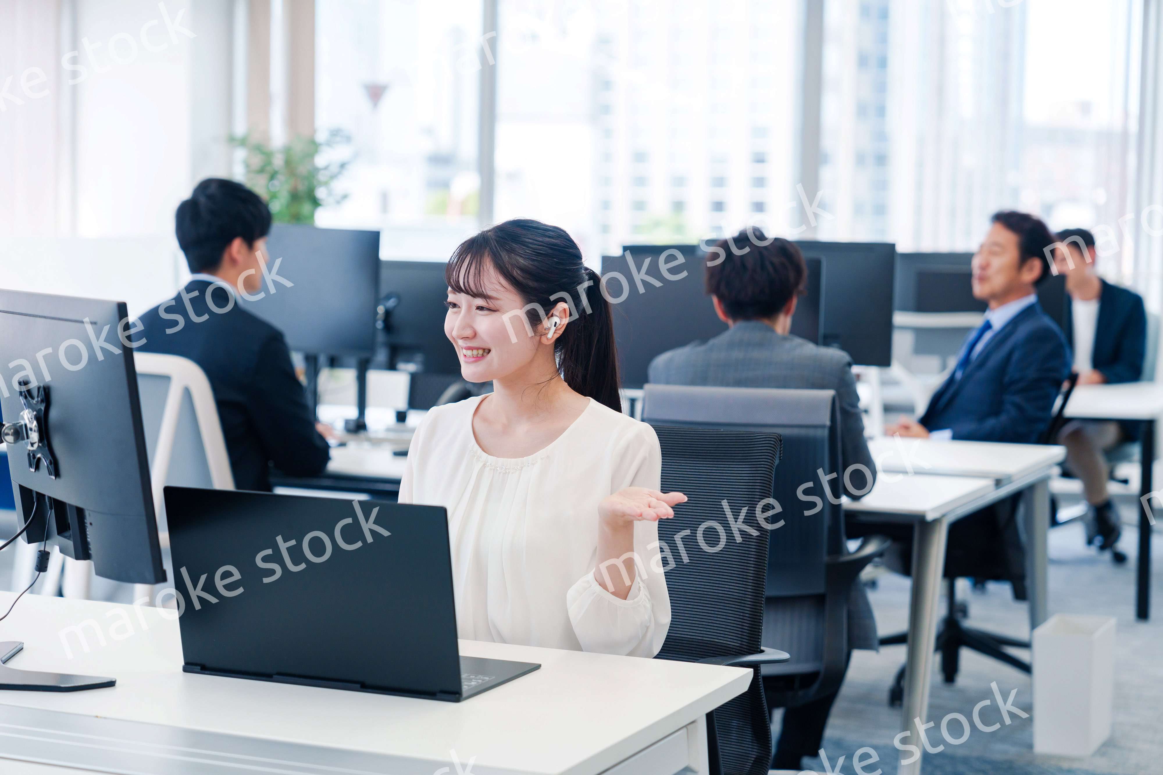 ワイヤレスイヤホンを使いオフィスでリモート会議をする女性