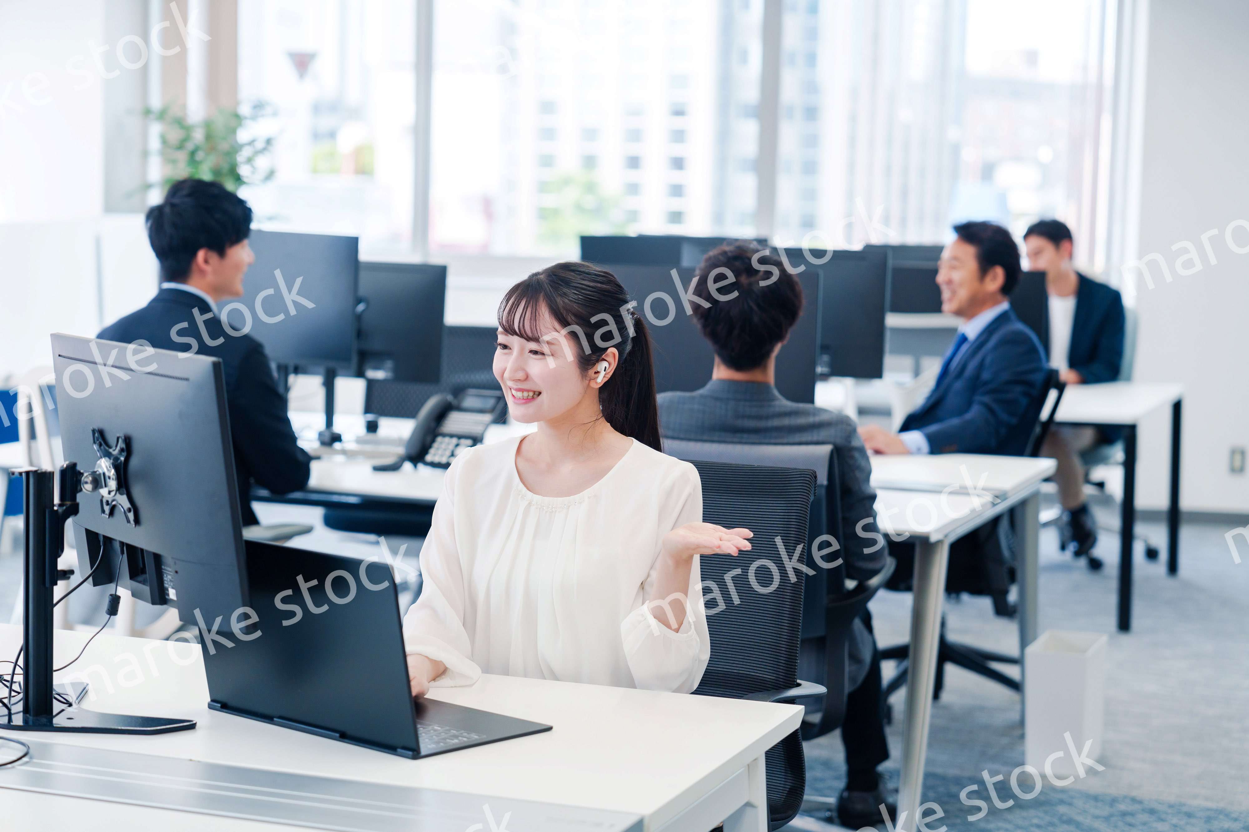 ワイヤレスイヤホンを使いオフィスでリモート会議をする女性