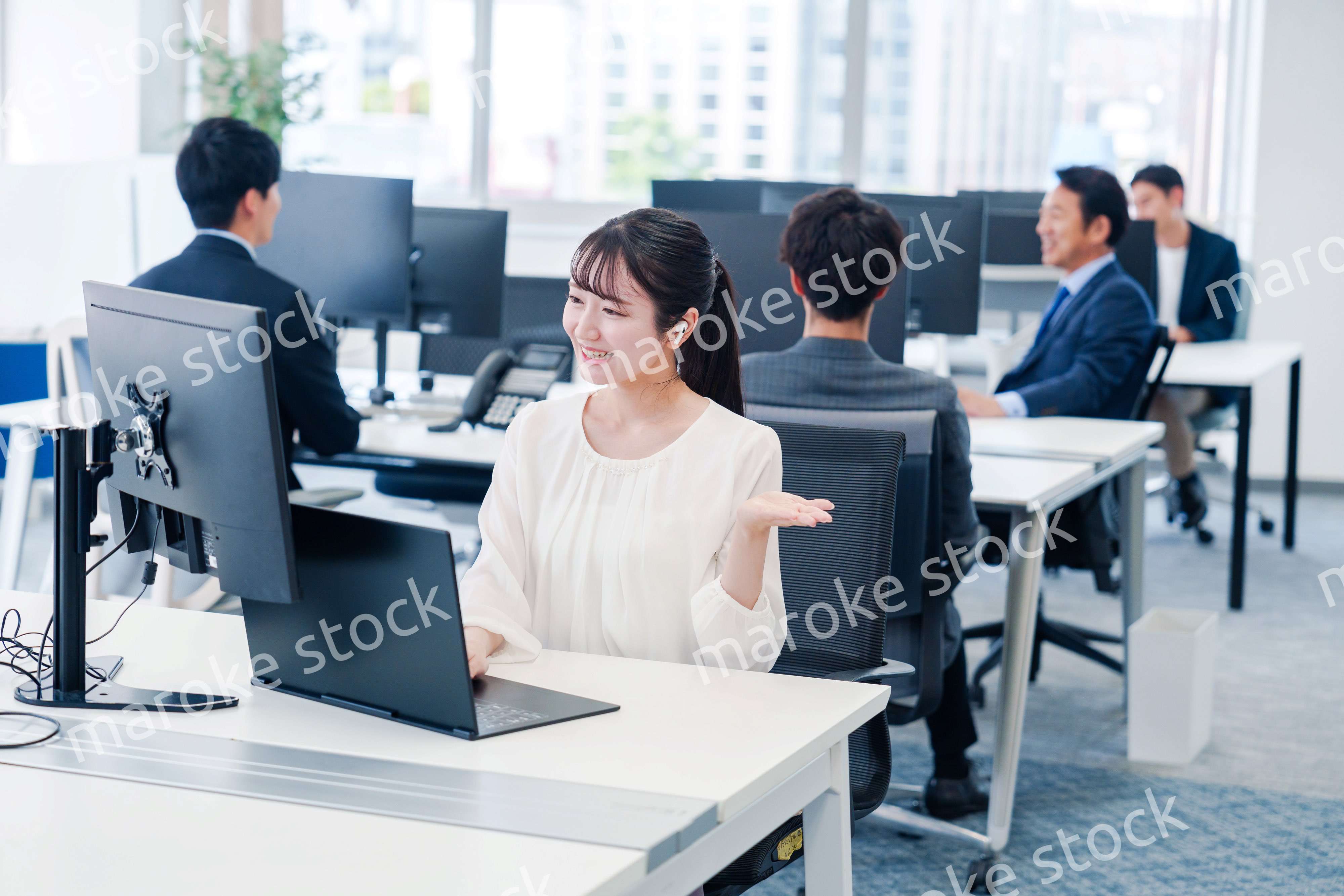 ワイヤレスイヤホンを使いオフィスでリモート会議をする女性