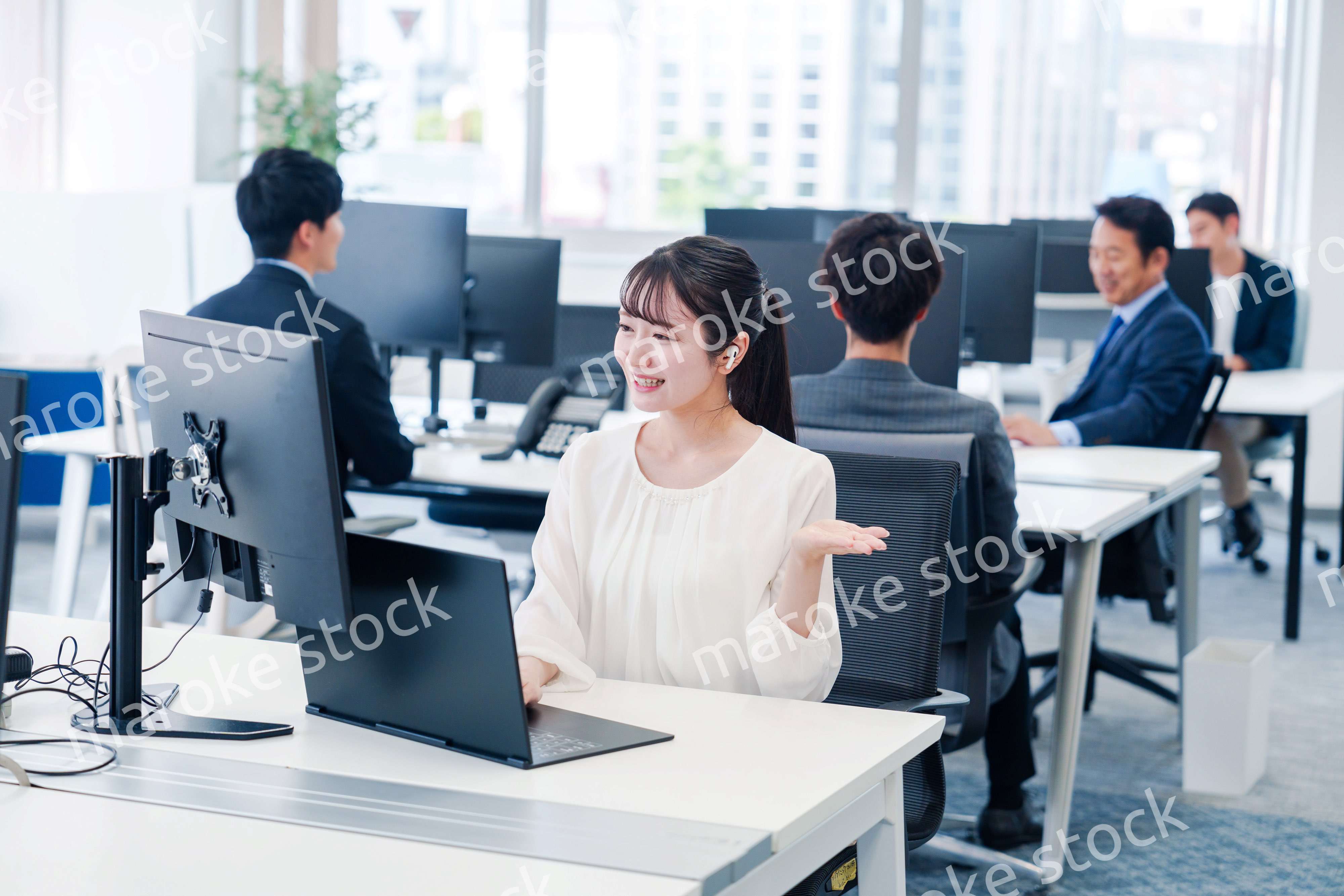 ワイヤレスイヤホンを使いオフィスでリモート会議をする女性