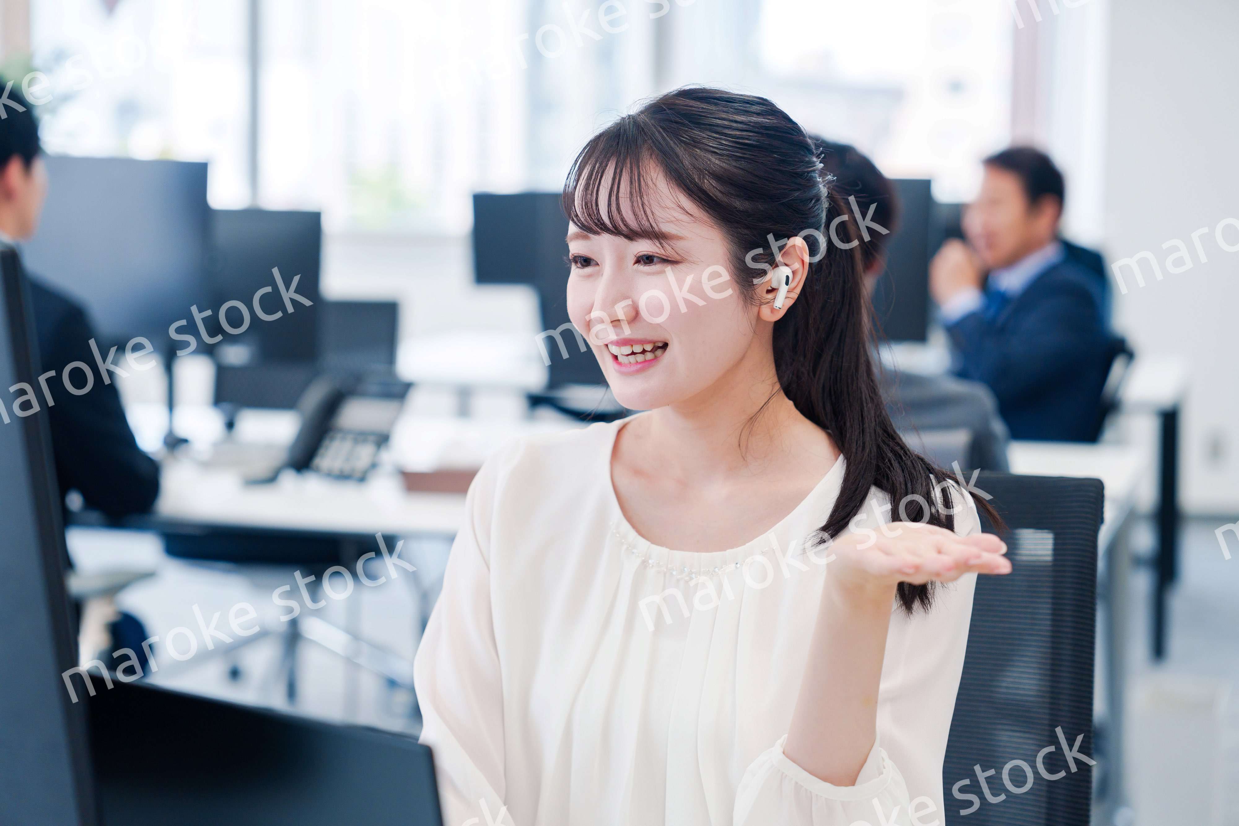 ワイヤレスイヤホンを使いオフィスでリモート会議をする女性