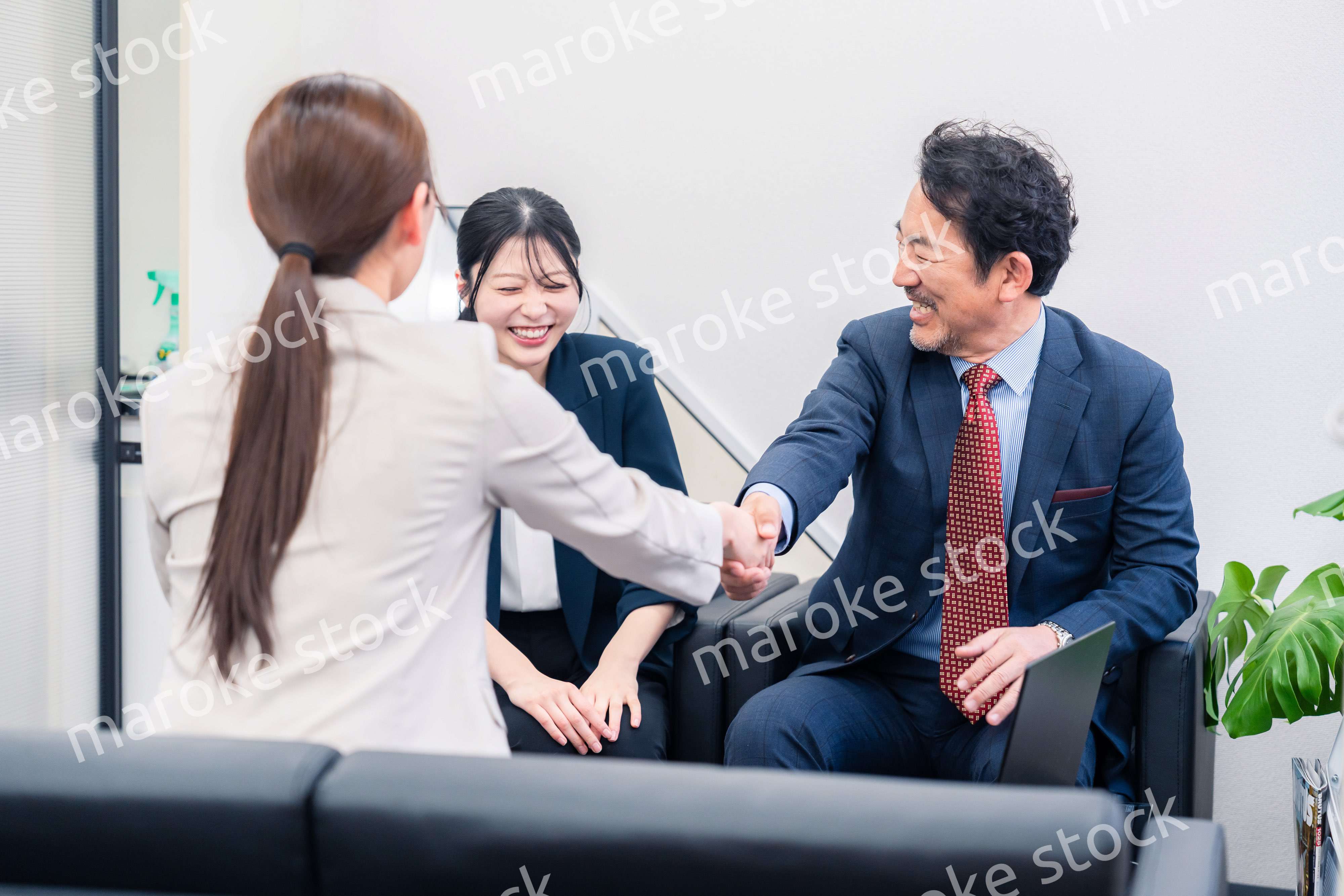 笑顔で握手を交わす3人のビジネスパーソン