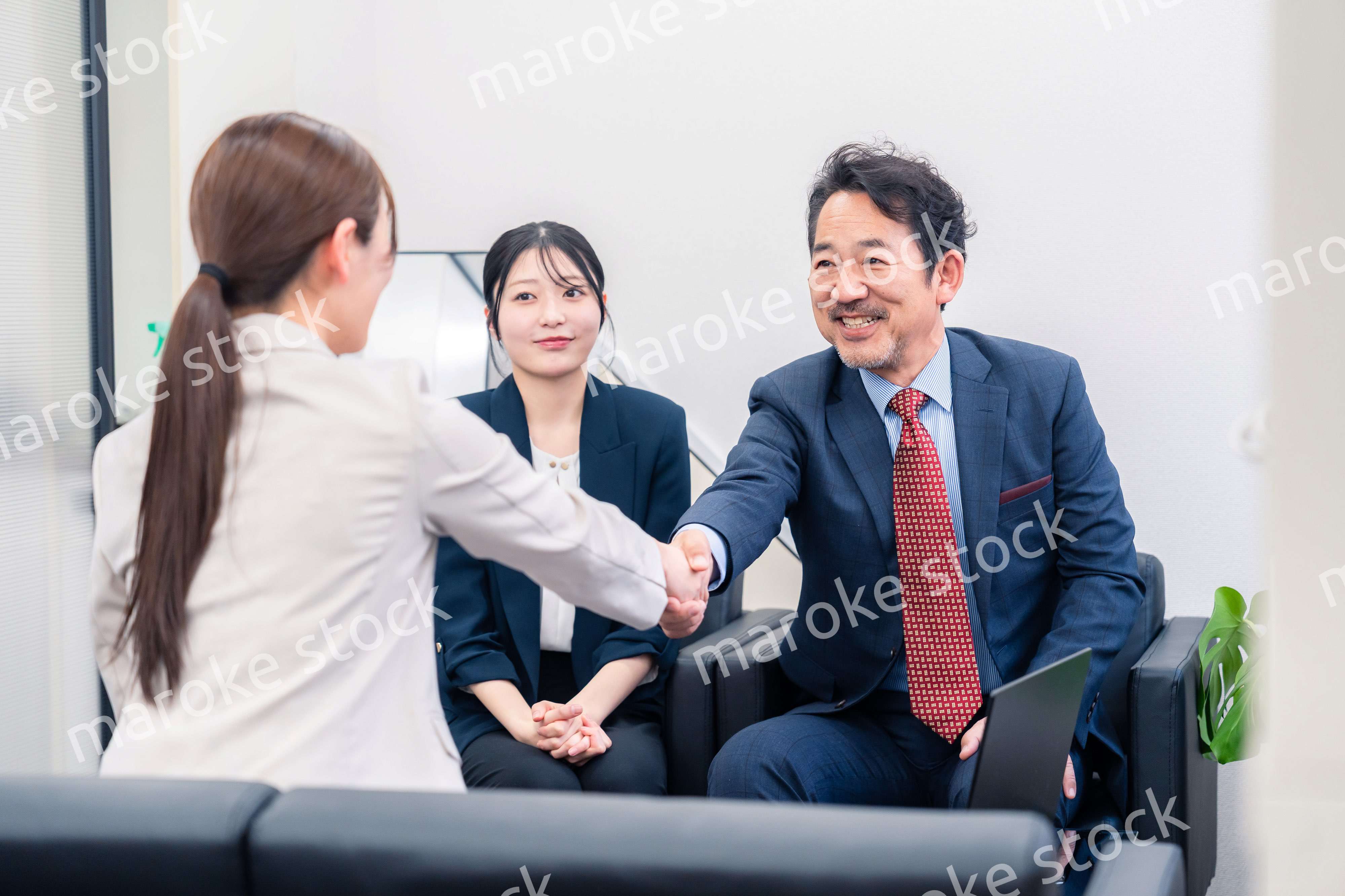 笑顔で握手を交わす3人のビジネスパーソン