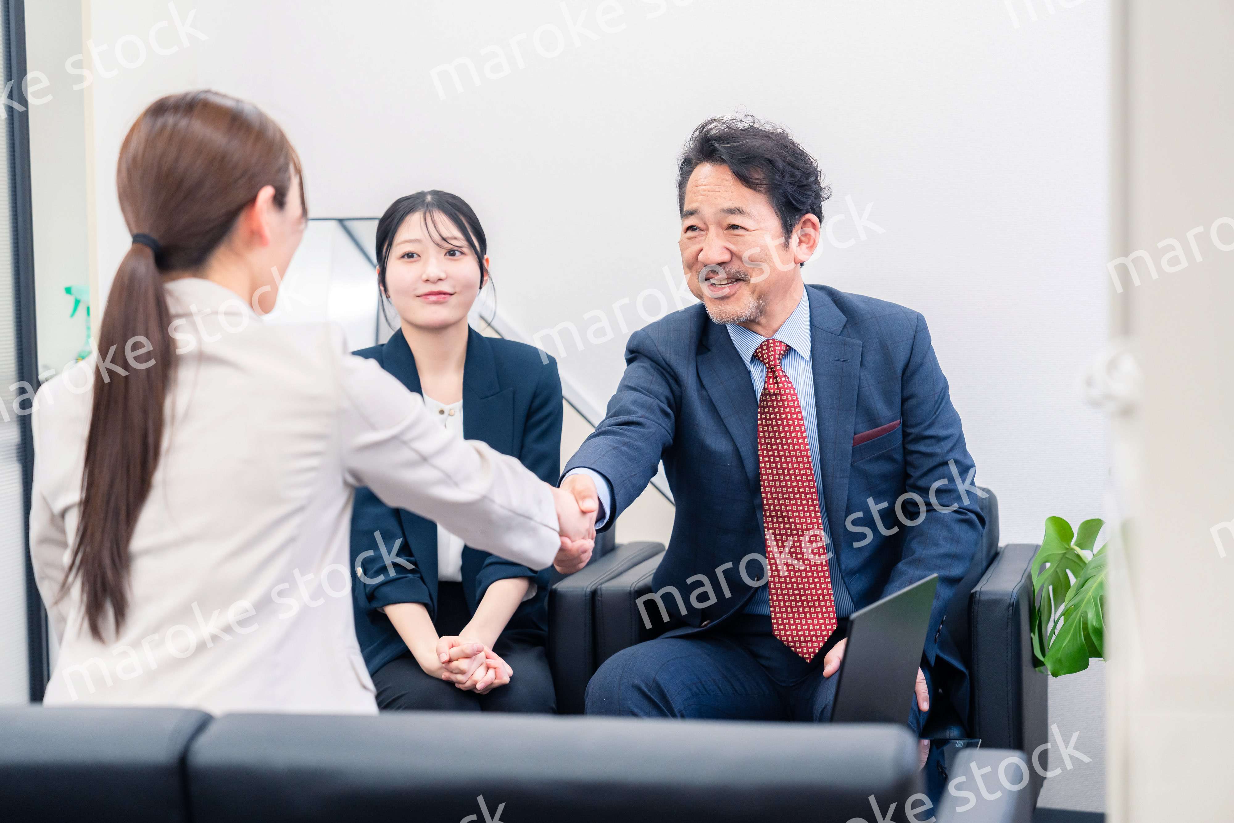 笑顔で握手を交わす3人のビジネスパーソン