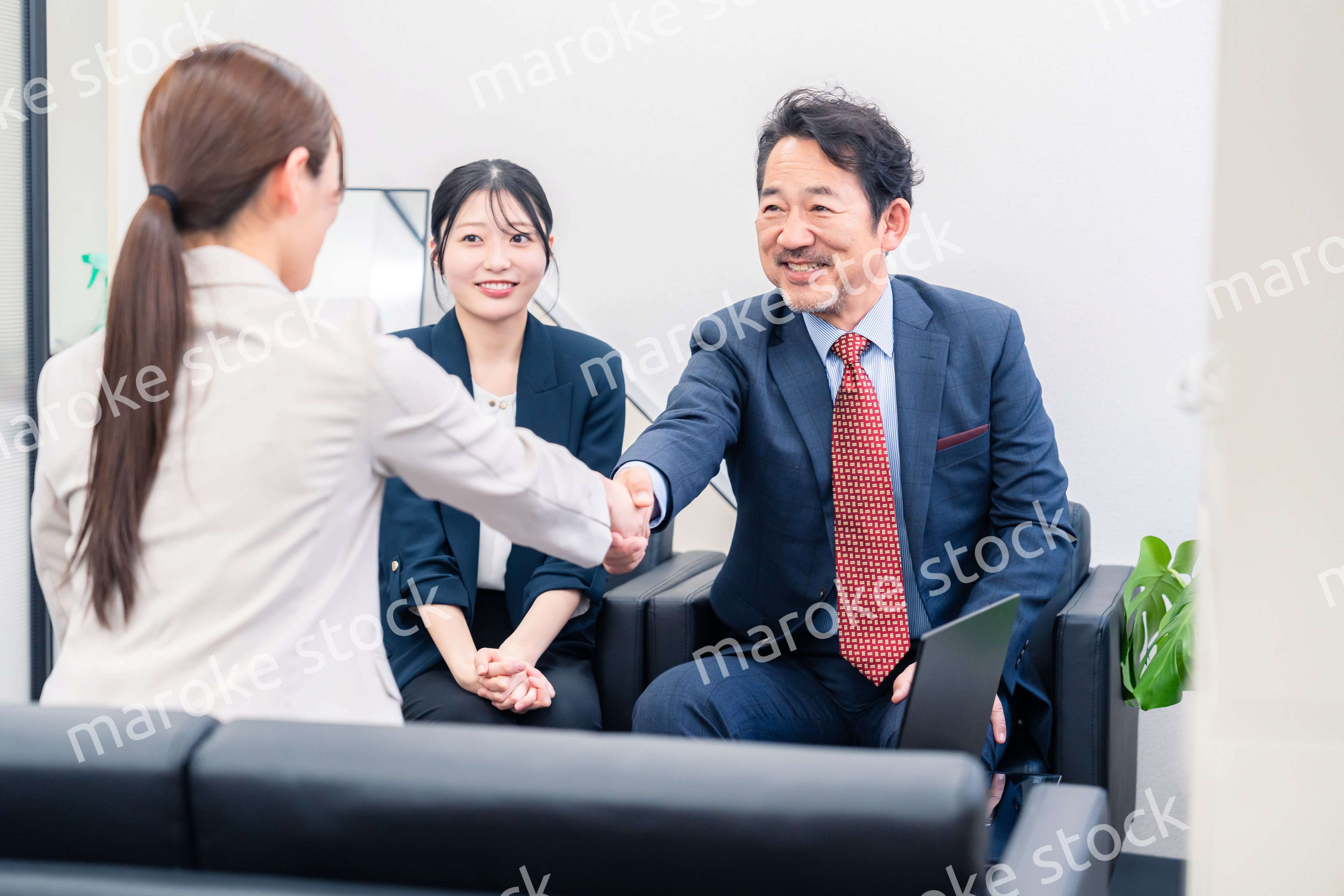 笑顔で握手を交わす3人のビジネスパーソン