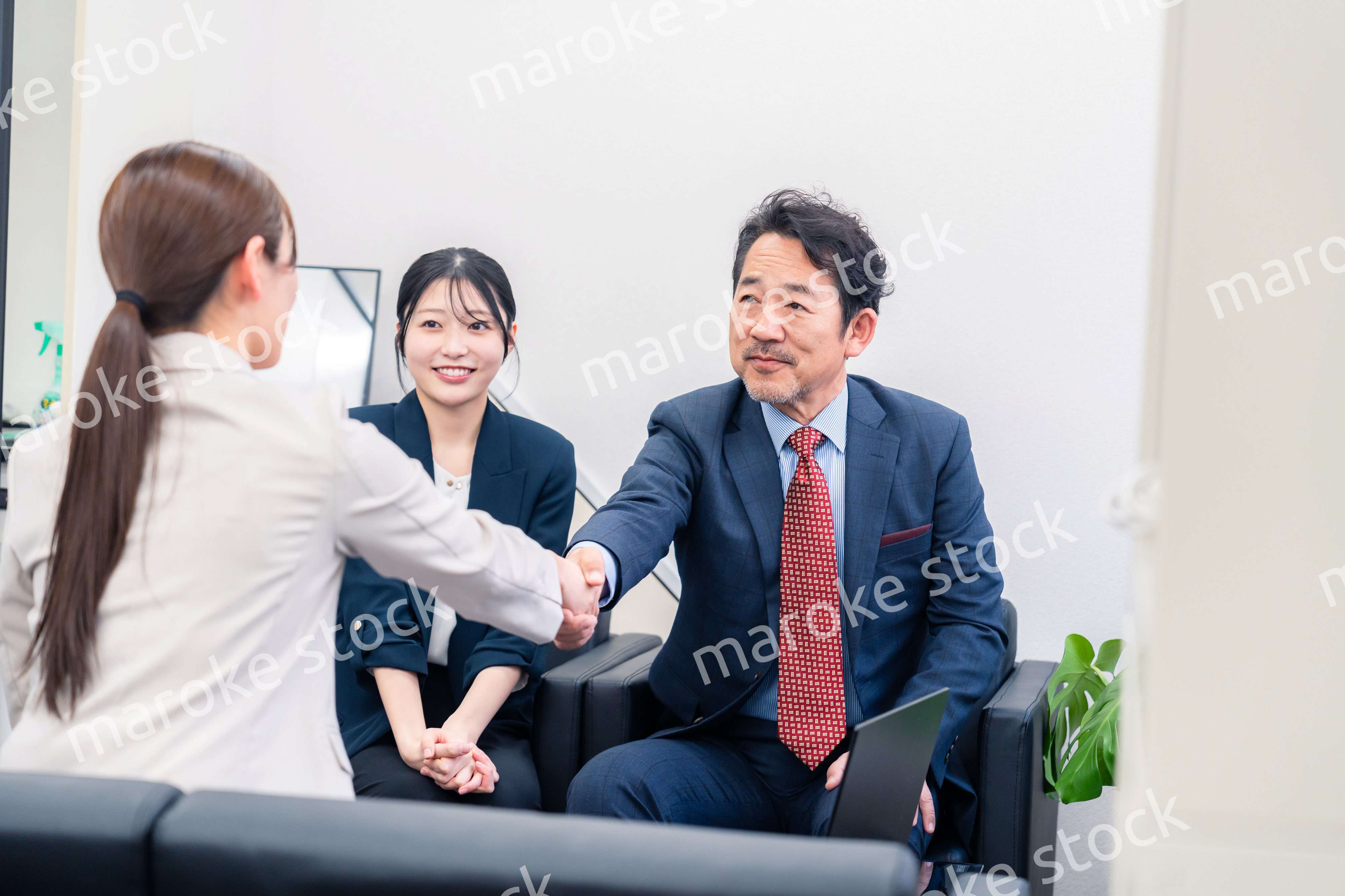 笑顔で握手を交わす3人のビジネスパーソン