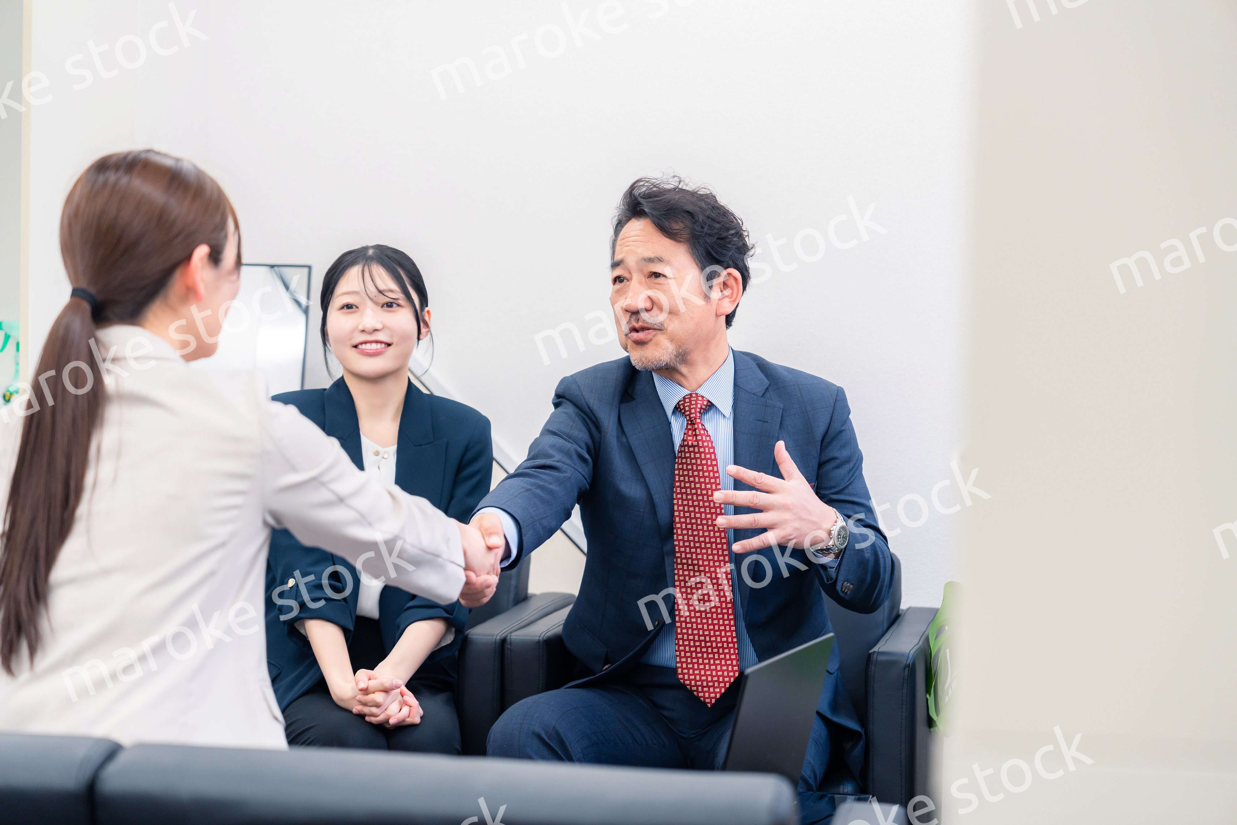 笑顔で握手を交わす3人のビジネスパーソン