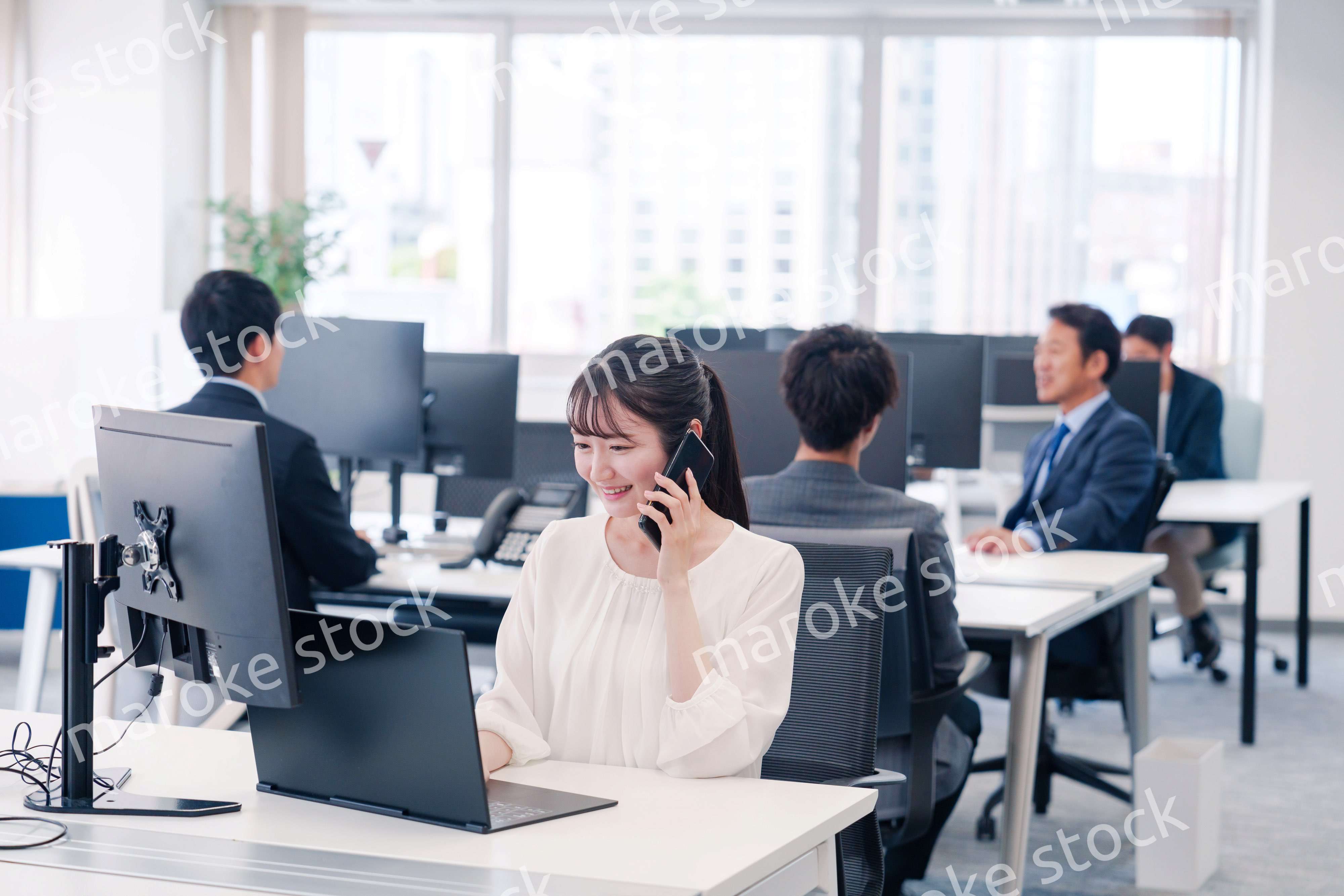 オフィスの中でスマホで通話をするビジネスパーソン