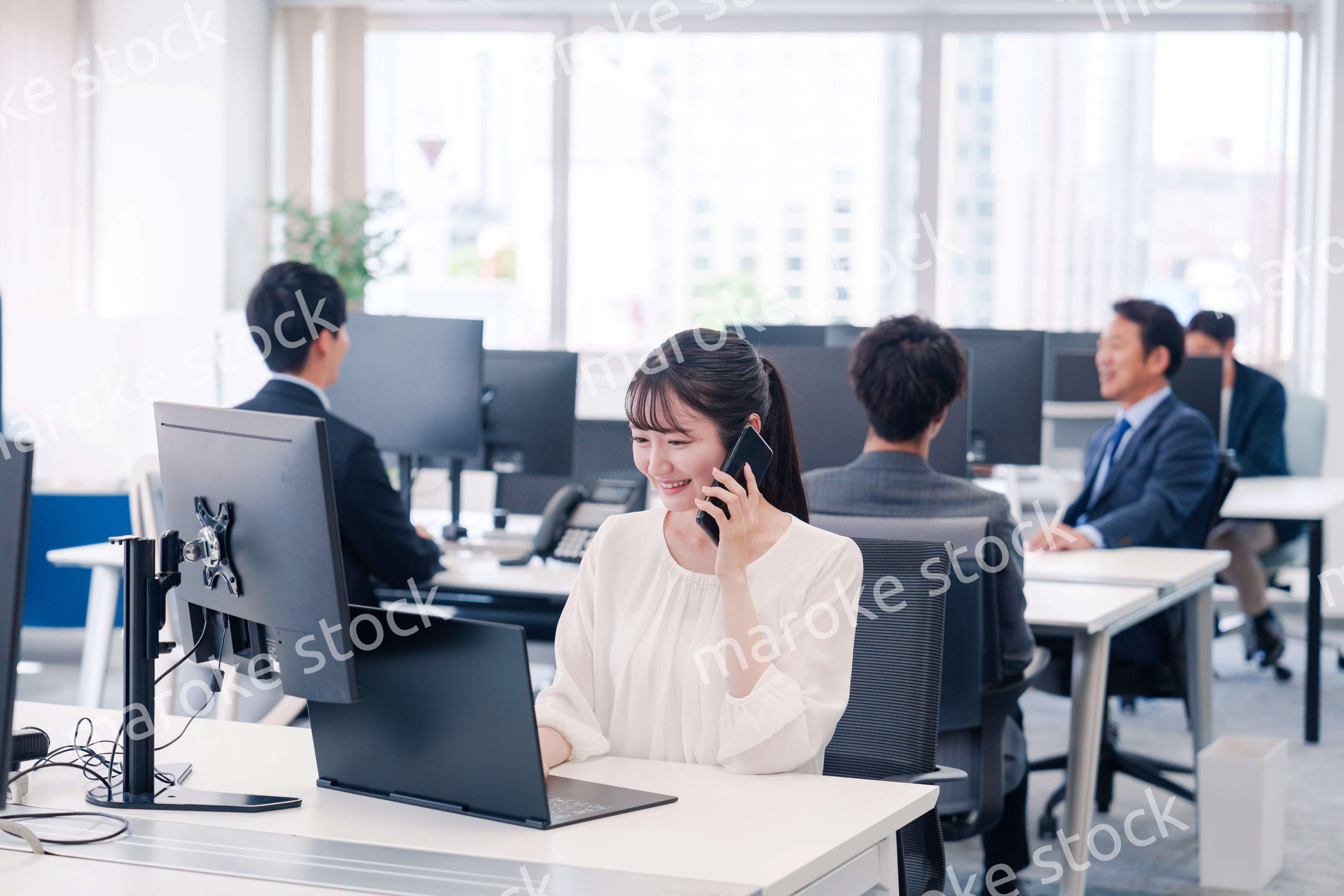 オフィスの中でスマホで通話をするビジネスパーソン