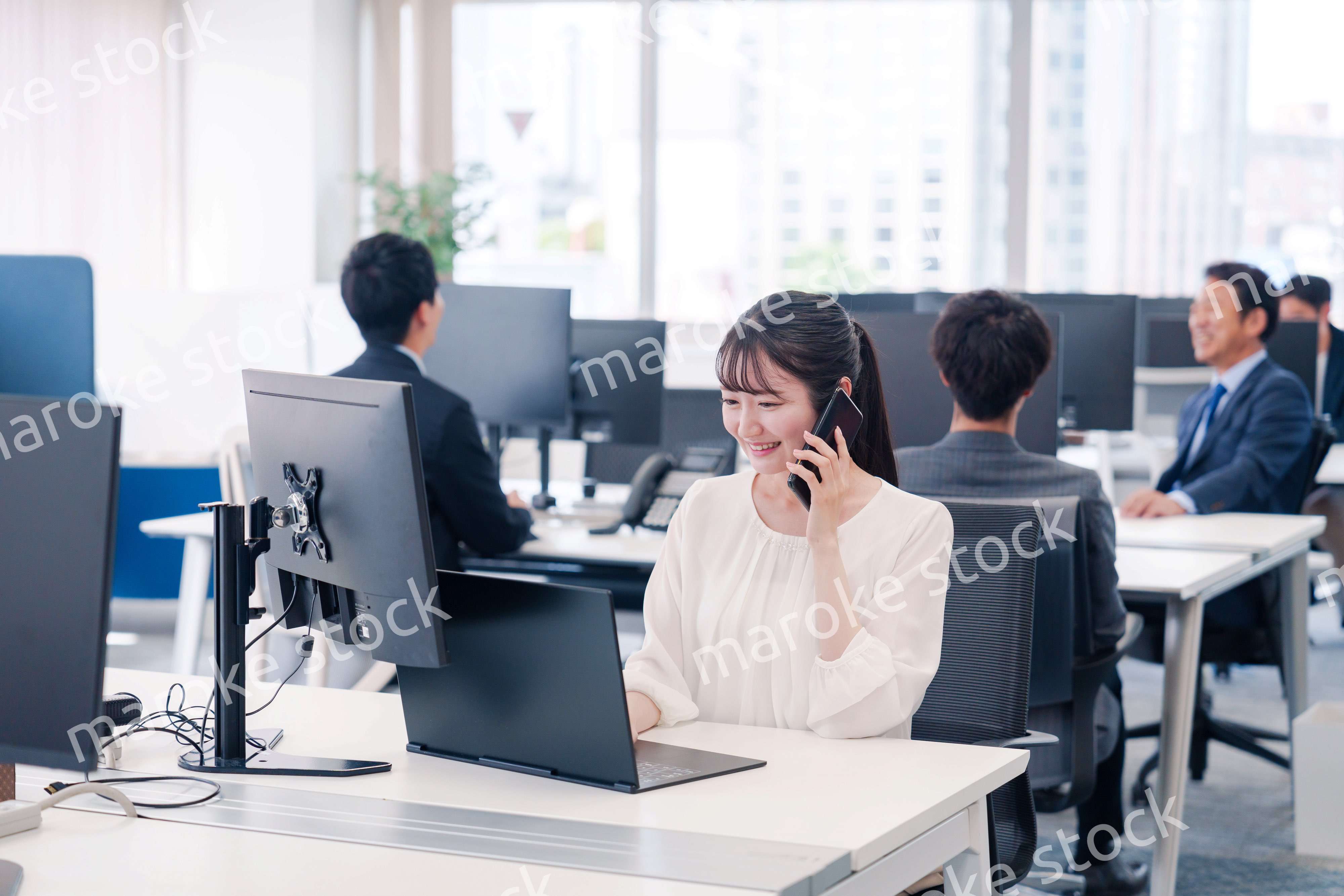 オフィスの中でスマホで通話をするビジネスパーソン