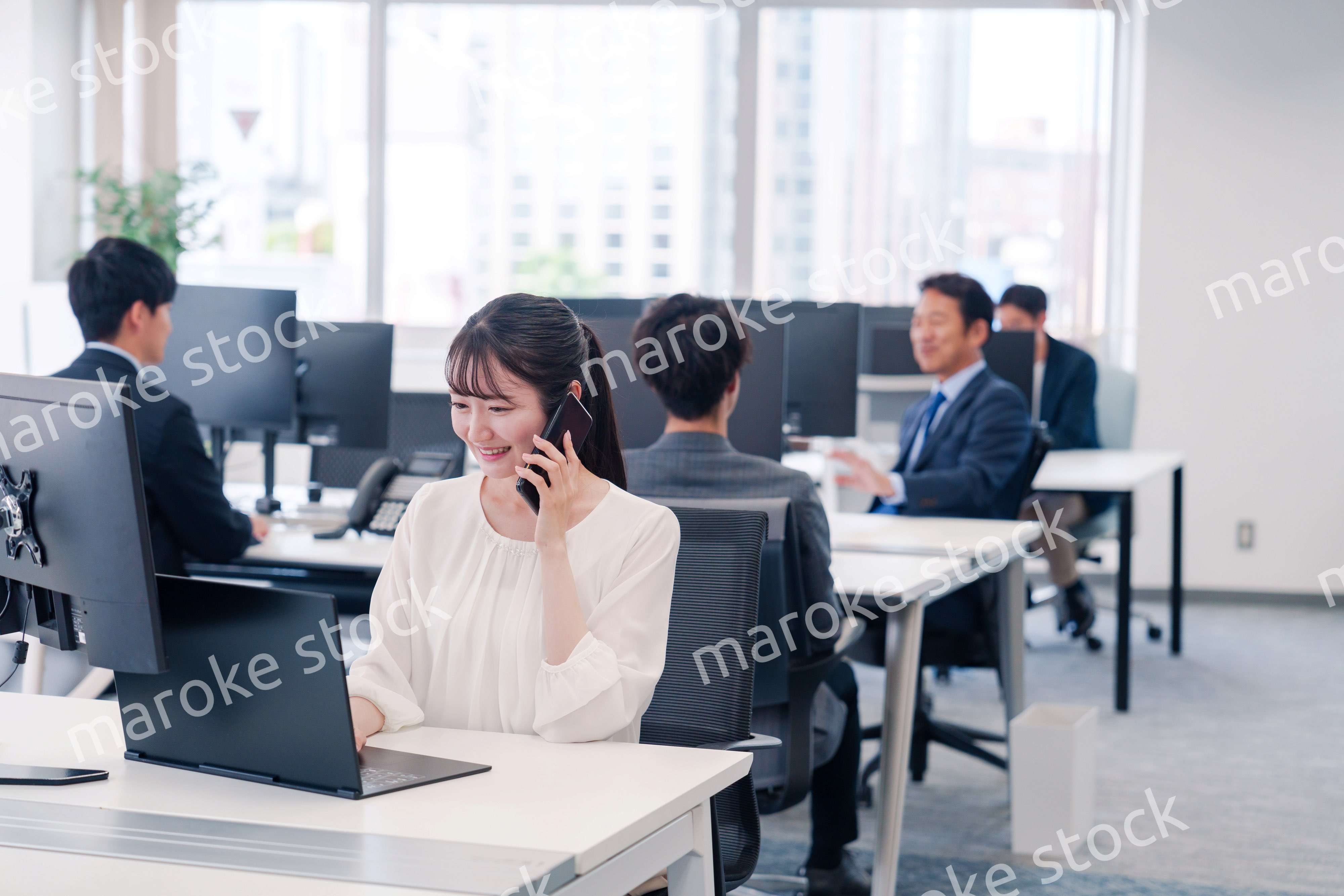 オフィスの中でスマホで通話をするビジネスパーソン