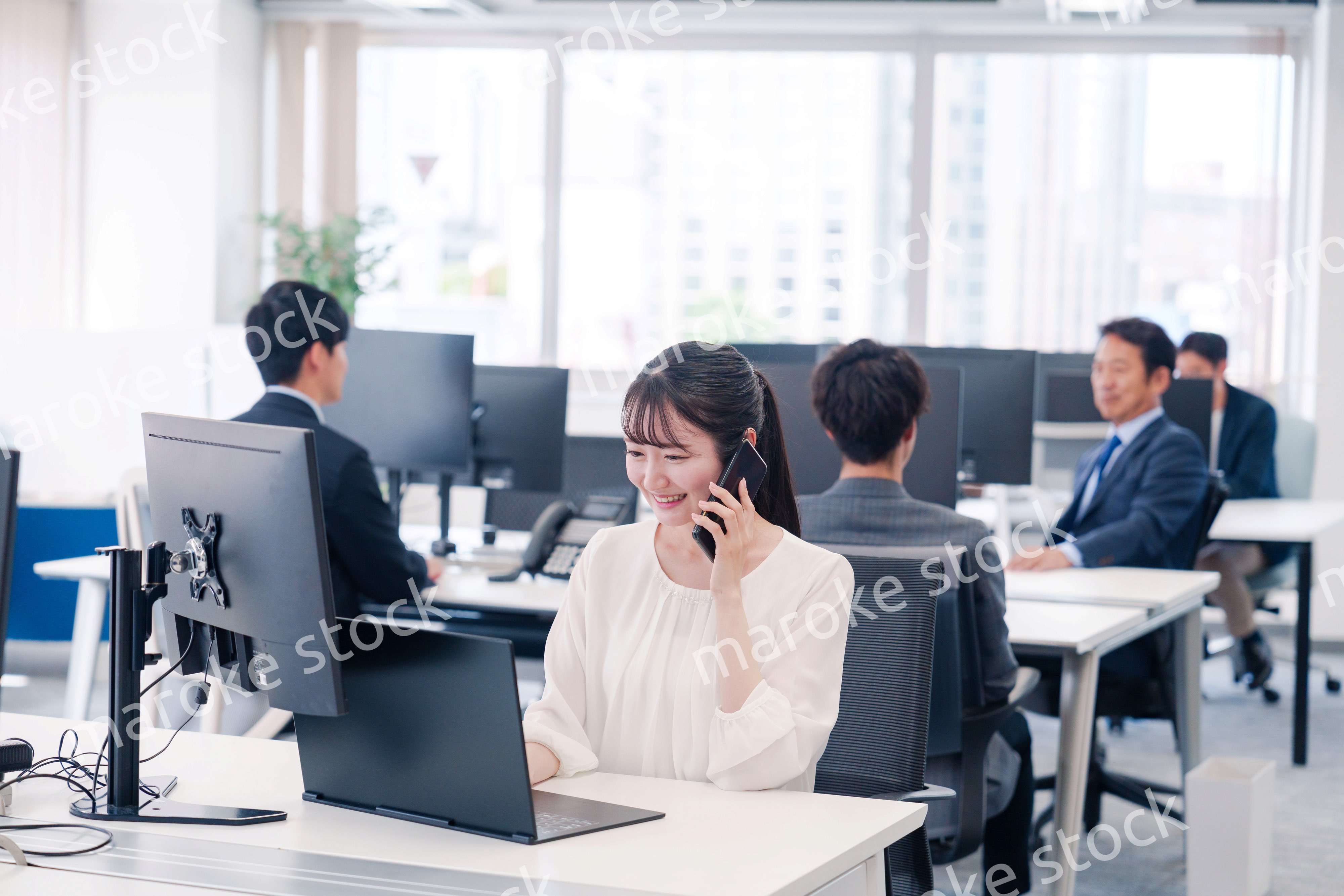 オフィスの中でスマホで通話をするビジネスパーソン