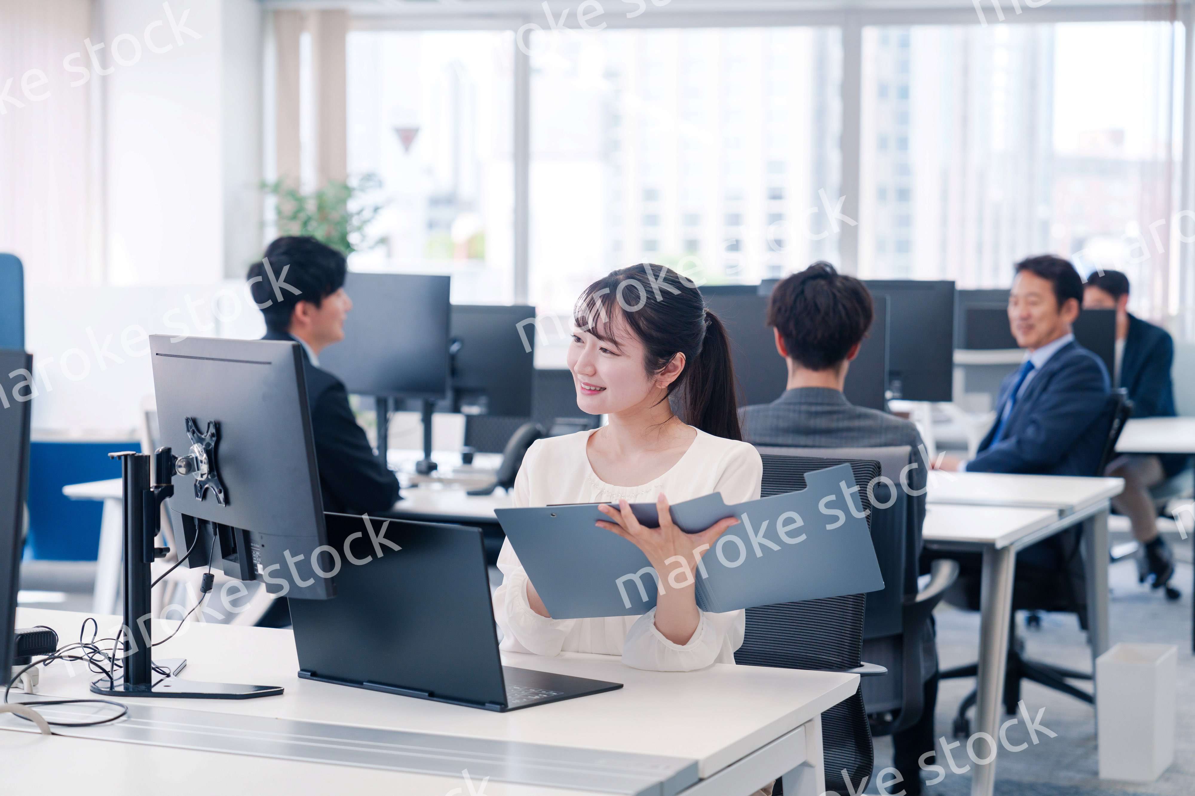 オフィスで笑顔でデスクワークをする若い女性